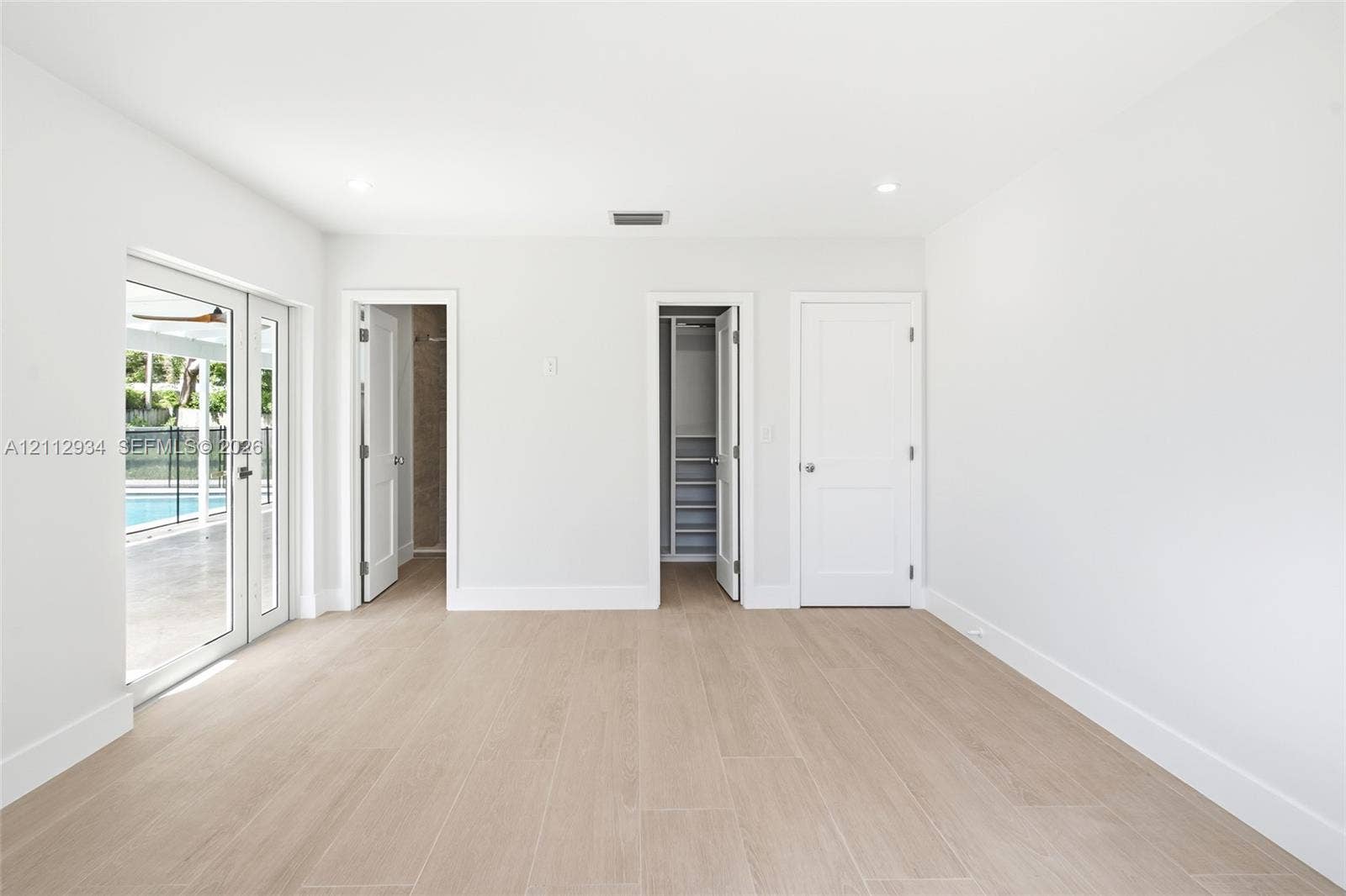 14620 SW 83rd Avenue, Palmetto Bay, Palmetto Bay, FL 33158 Interior space featuring neutral walls, wood-finish tile flooring, recessed lighting, double glass-panel doors, and built-in closet shelving