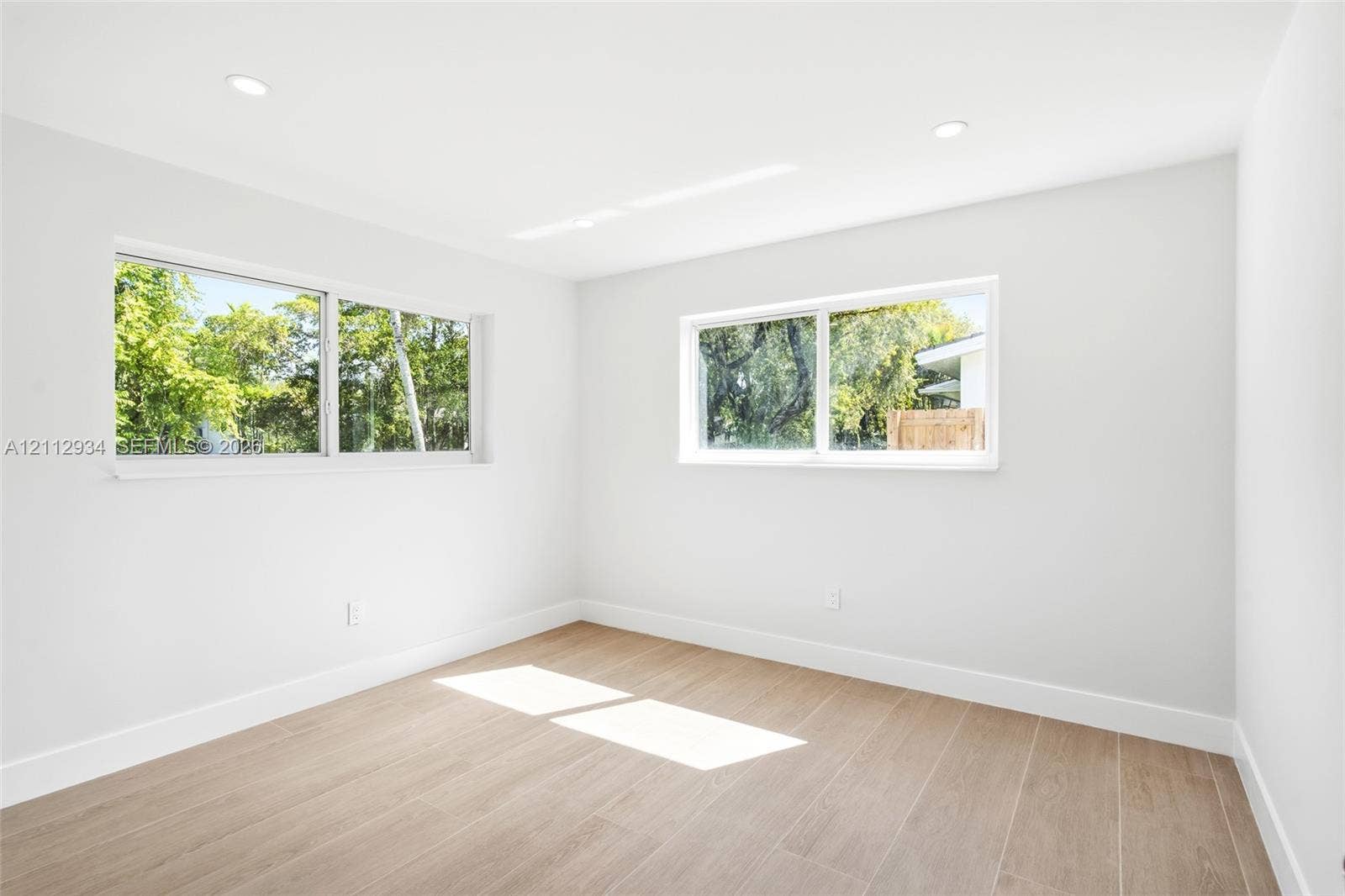 14620 SW 83rd Avenue, Palmetto Bay, Palmetto Bay, FL 33158 Neutral-toned interior space featuring wood-finish flooring, recessed lighting, and multiple sliding windows