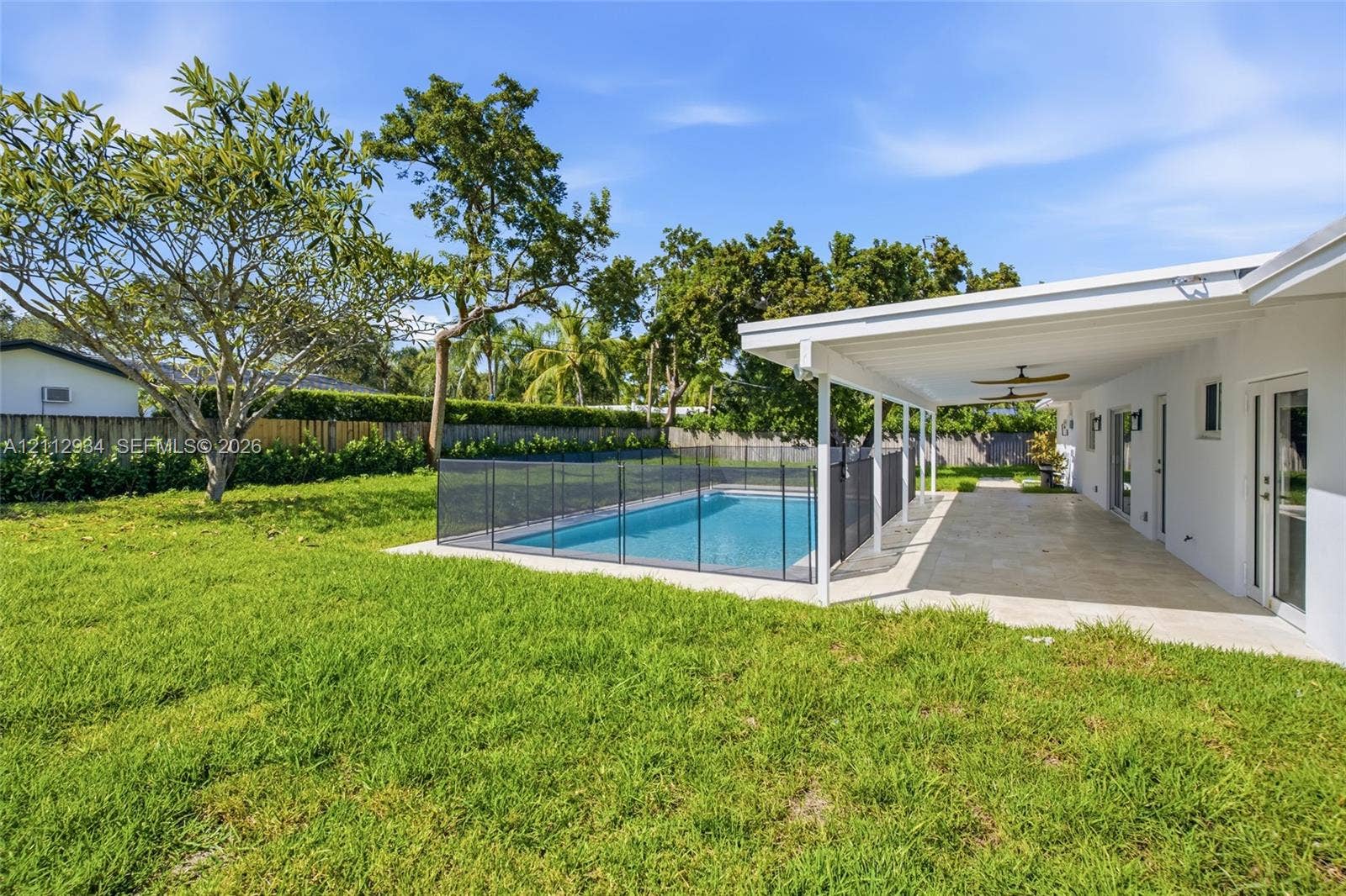 14620 SW 83rd Avenue, Palmetto Bay, Palmetto Bay, FL 33158 Backyard featuring a swimming pool with a black safety fence, a covered paved patio, and mature landscaping