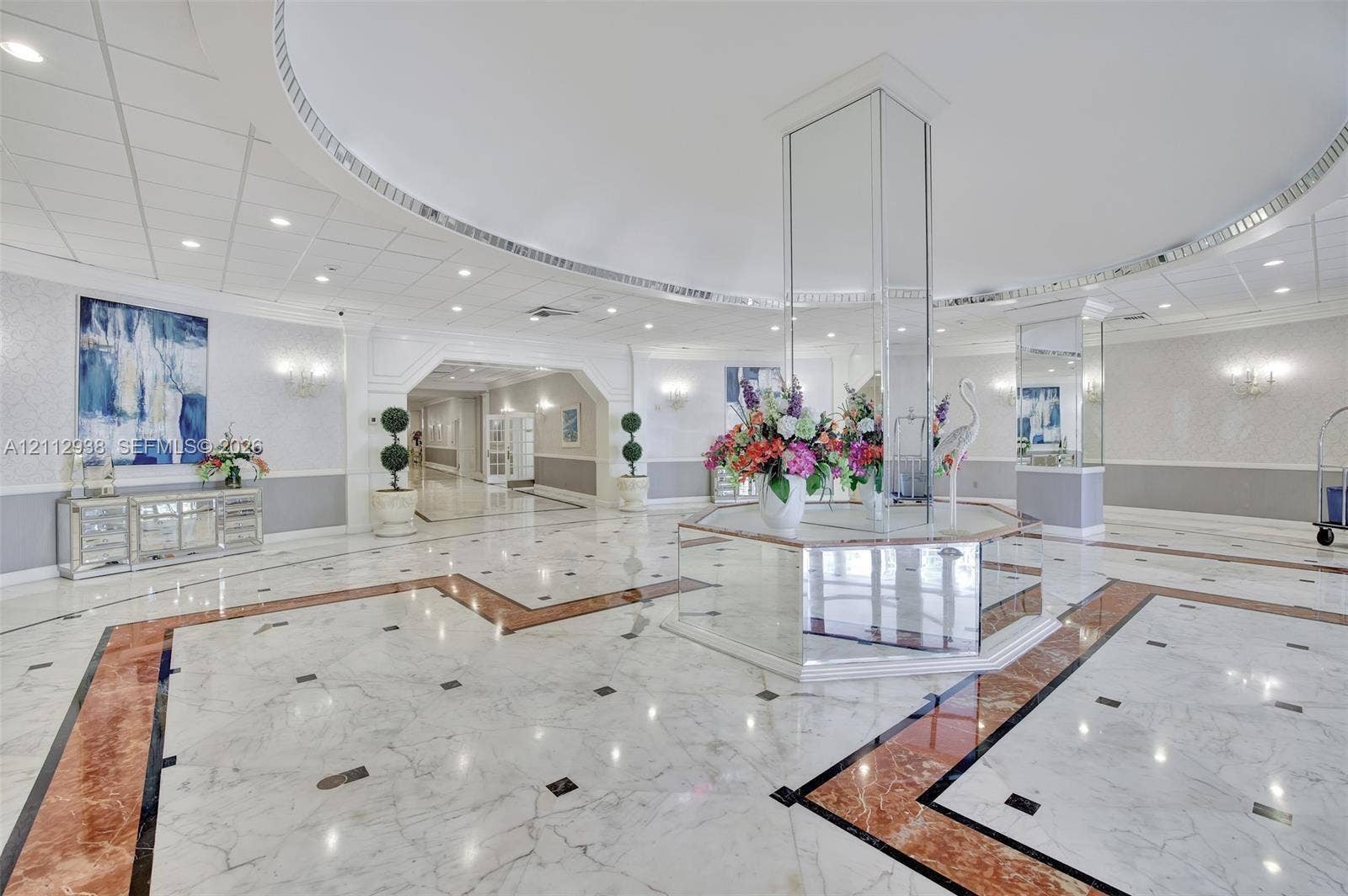 3800 S Ocean Drive, #801, Hollywood, FL 33019 Grand lobby featuring stone flooring with intricate inlay borders, a mirrored central pillar, recessed lighting, and crown molding