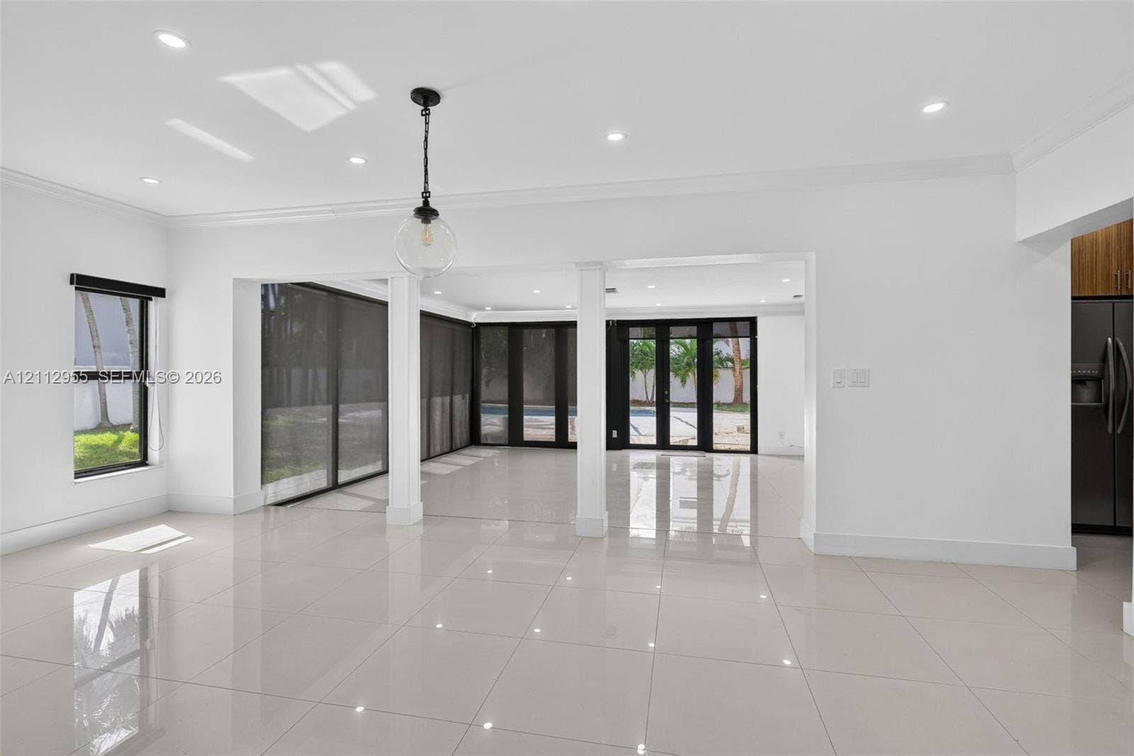 549 NE 12th Avenue, Fort Lauderdale, FL 33301 Large-format polished tile flooring, recessed ceiling lighting, structural support columns, black-framed sliding glass doors, and a decorative globe pendant fixture