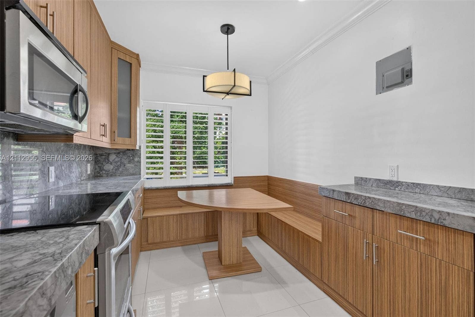 549 NE 12th Avenue, Fort Lauderdale, FL 33301 Kitchen featuring wood-finish cabinetry, stone-surface countertops, built-in breakfast nook with integrated bench seating, polished tile flooring, and shutter window treatments
