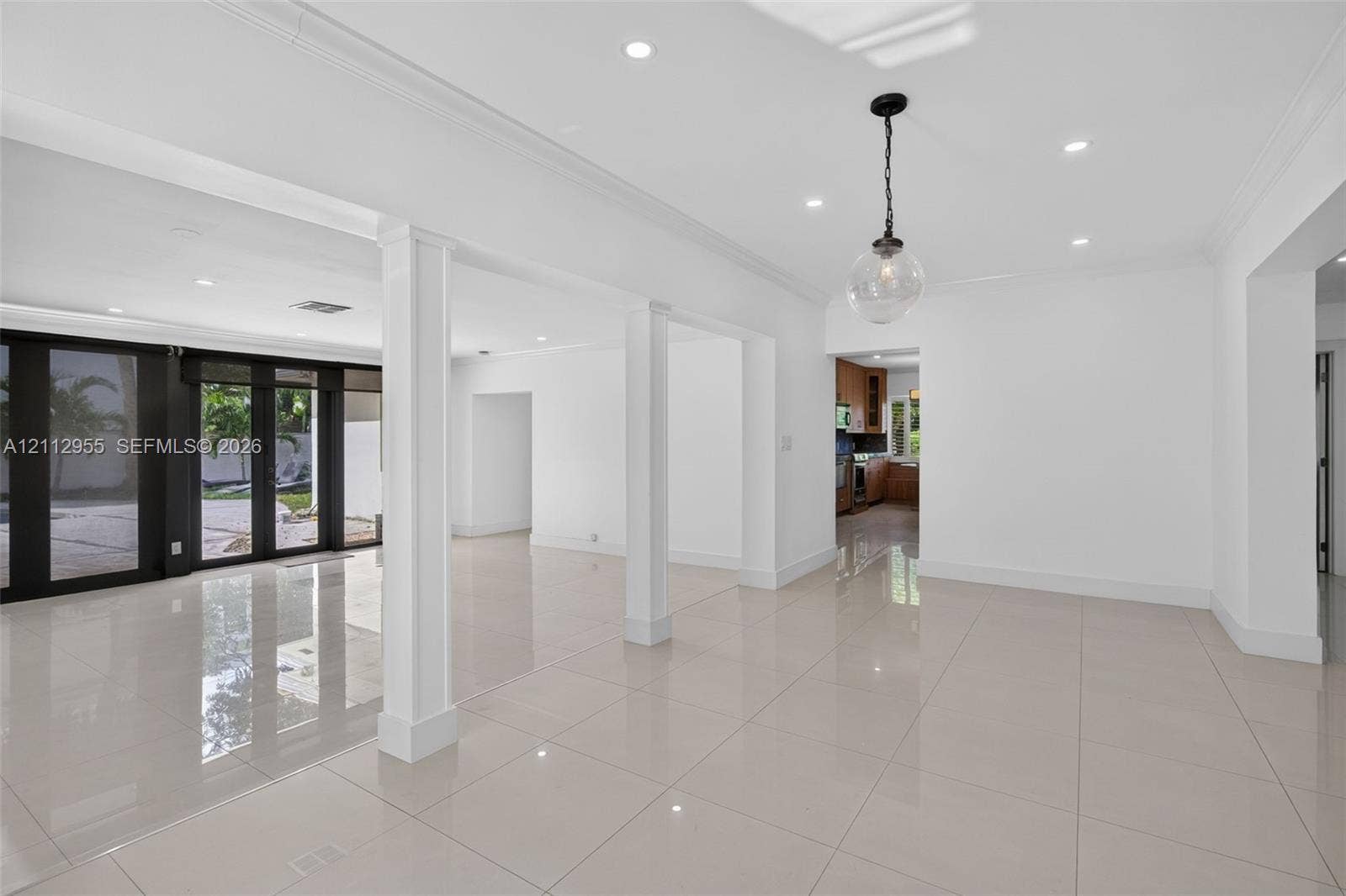549 NE 12th Avenue, Fort Lauderdale, FL 33301 Open-concept interior featuring large-format polished tile flooring, recessed lighting, architectural columns, and dark-framed glass paneled doors