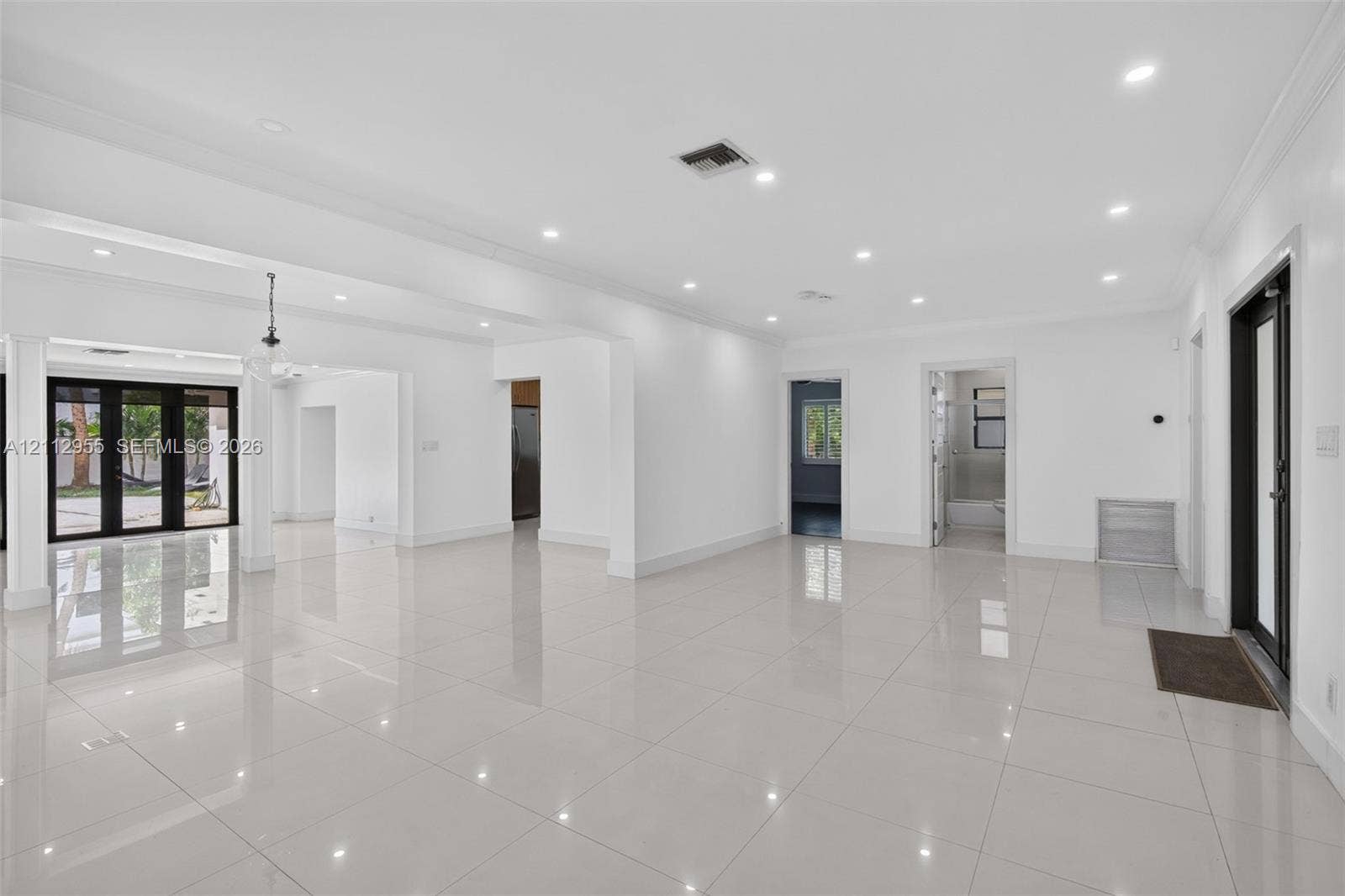 549 NE 12th Avenue, Fort Lauderdale, FL 33301 Open-concept interior featuring large-format tile flooring, recessed ceiling lighting, crown molding, and black-framed glass patio doors