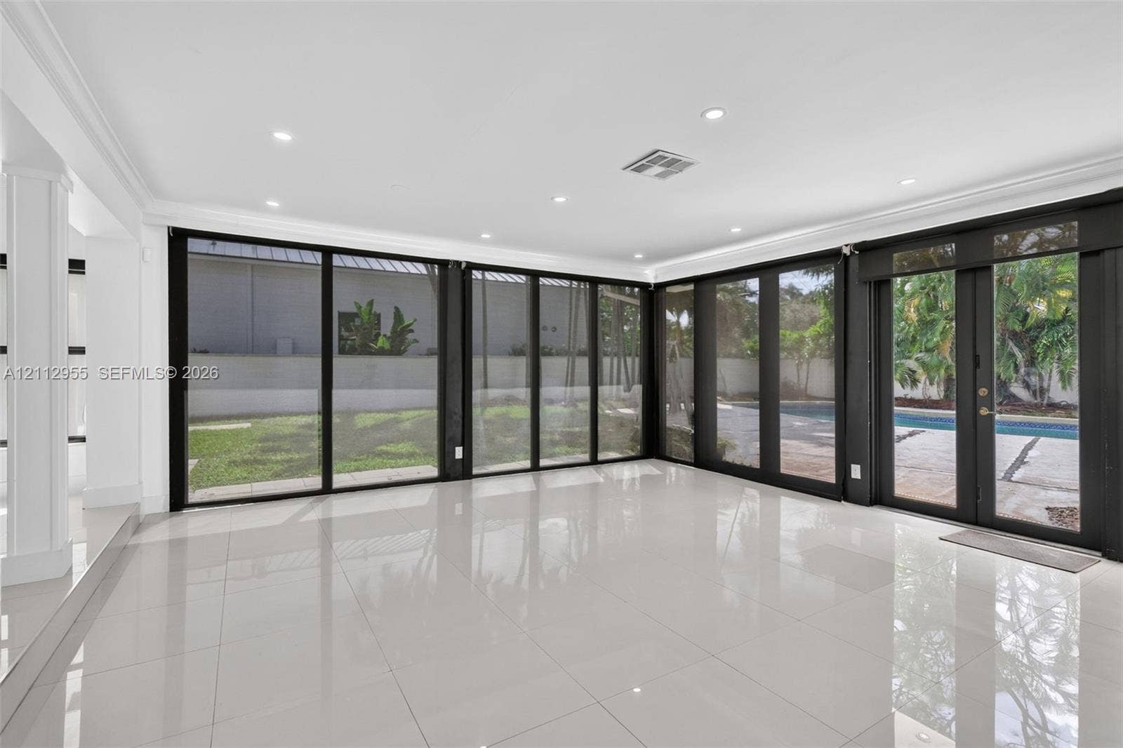 549 NE 12th Avenue, Fort Lauderdale, FL 33301 Polished porcelain tile flooring, recessed LED lighting, and expansive floor-to-ceiling black-framed glass wall panels opening to a rear exterior patio and pool area