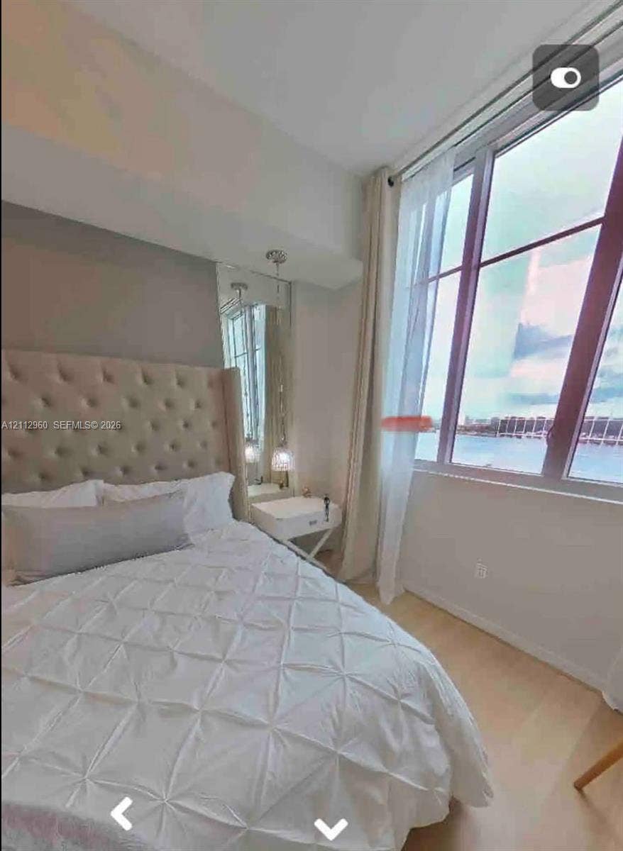 Floor-to-ceiling windows featuring water scenery, wood-finish flooring, and built-in mirror paneling