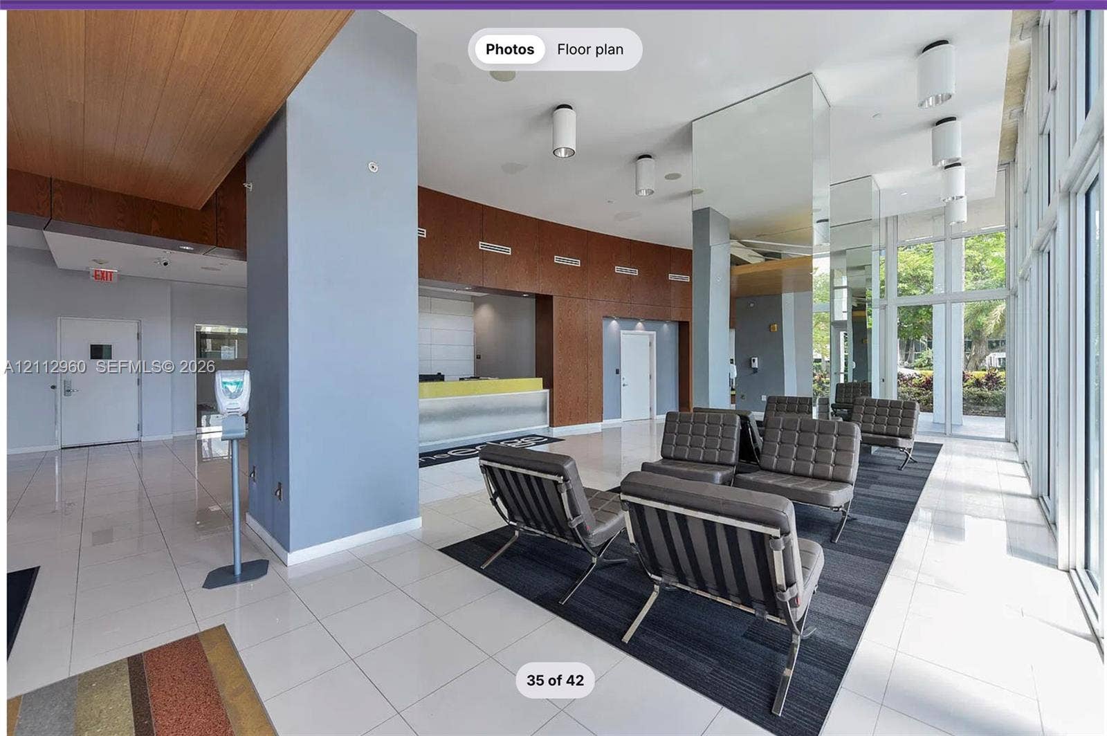 Lobby featuring a wood-panel accent wall, floor-to-ceiling glass windows, ceramic tile flooring, and recessed cylinder lighting