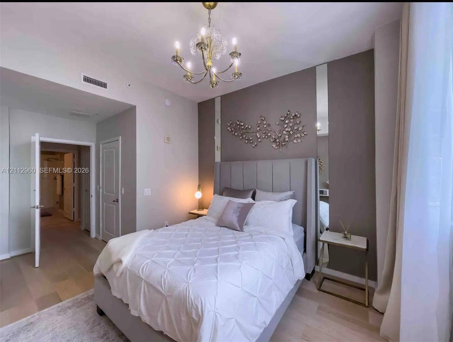 Multi-tone wall finish with vertical accent mirroring, multi-arm crystal chandelier, wood-finish flooring, and solid-core interior doors