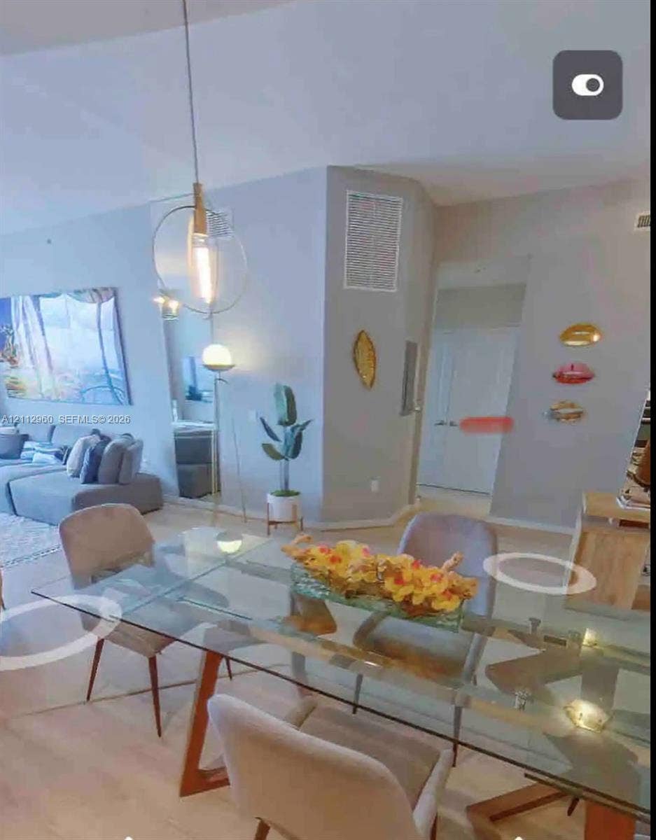 Open-concept interior featuring light wood-finish flooring, high ceilings, and a suspended metal-frame pendant light fixture
