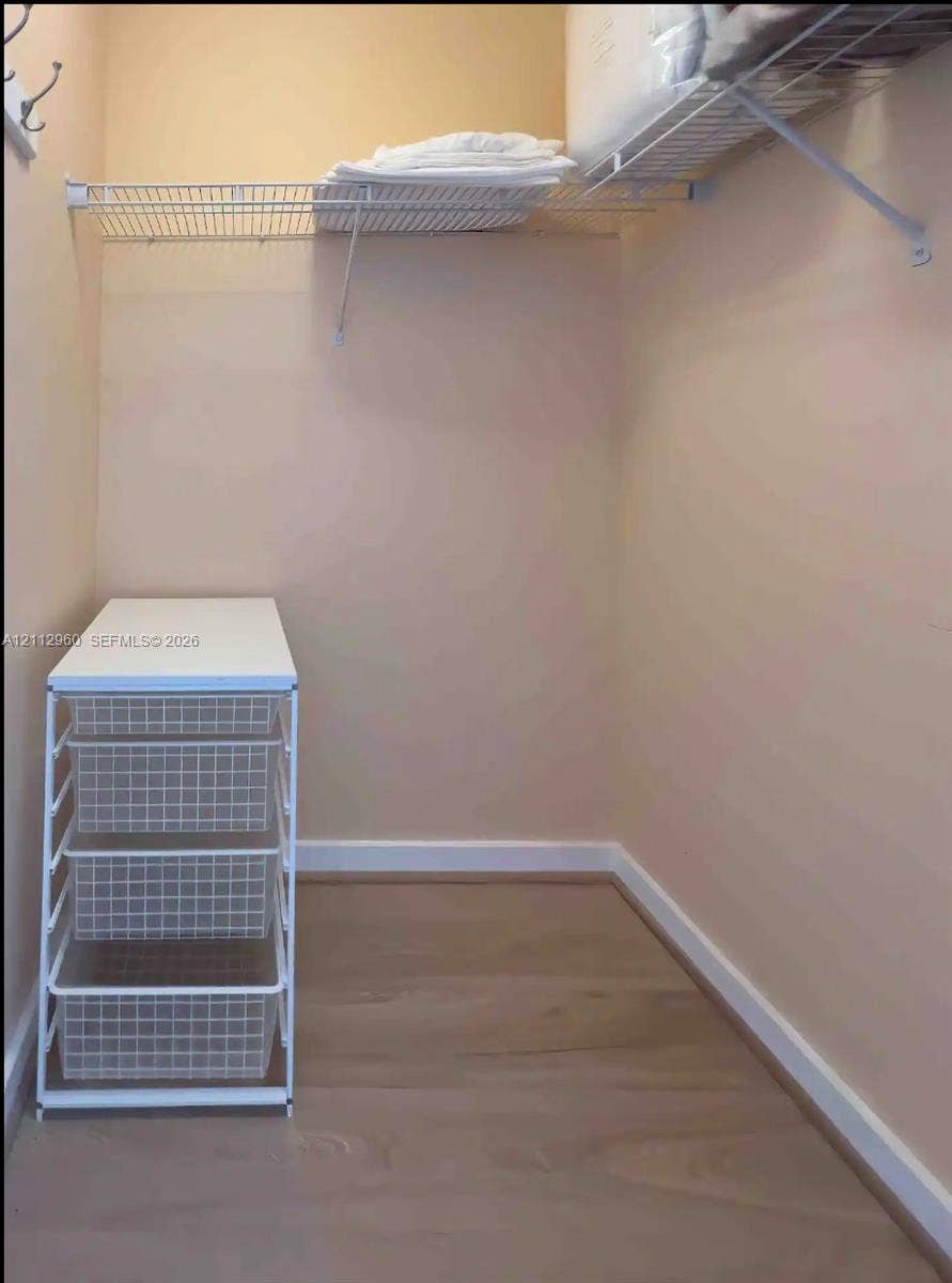 Storage area featuring wood-finish flooring, metal wire shelving, and a white built-in multi-drawer organization unit