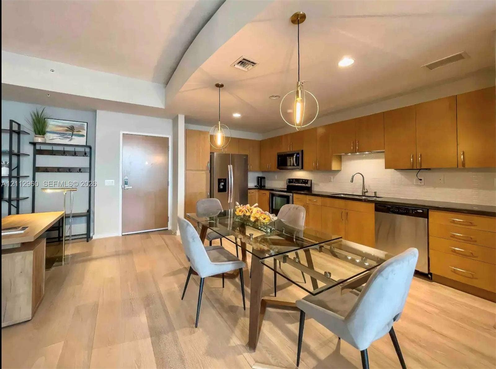 Kitchen featuring flat-panel wood cabinetry, dark stone countertops, stainless steel appliances, recessed lighting, and geometric pendant light fixtures