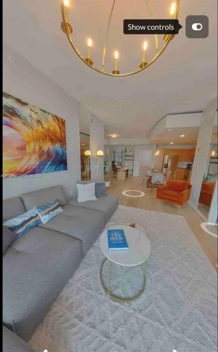 Open-concept space featuring light wood-finish flooring, a metallic circular chandelier, full-height wall mirrors, and recessed lighting