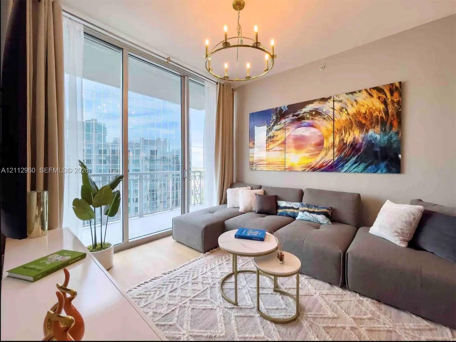 Floor-to-ceiling sliding glass doors, brass-finish circular chandelier, and neutral wall tones