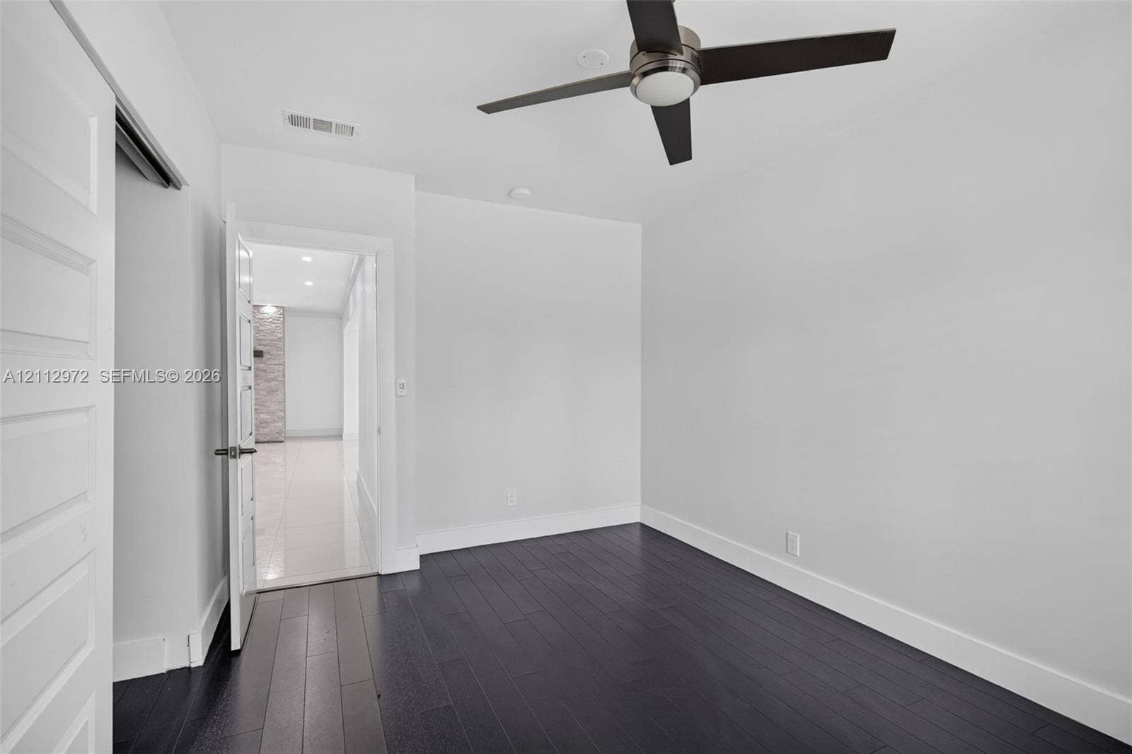 549 NE 12th Avenue, #0, Fort Lauderdale, Fort Lauderdale, FL 33301 Room featuring dark wood-finish flooring, a multi-blade ceiling fan with integrated lighting, and a solid-core interior door