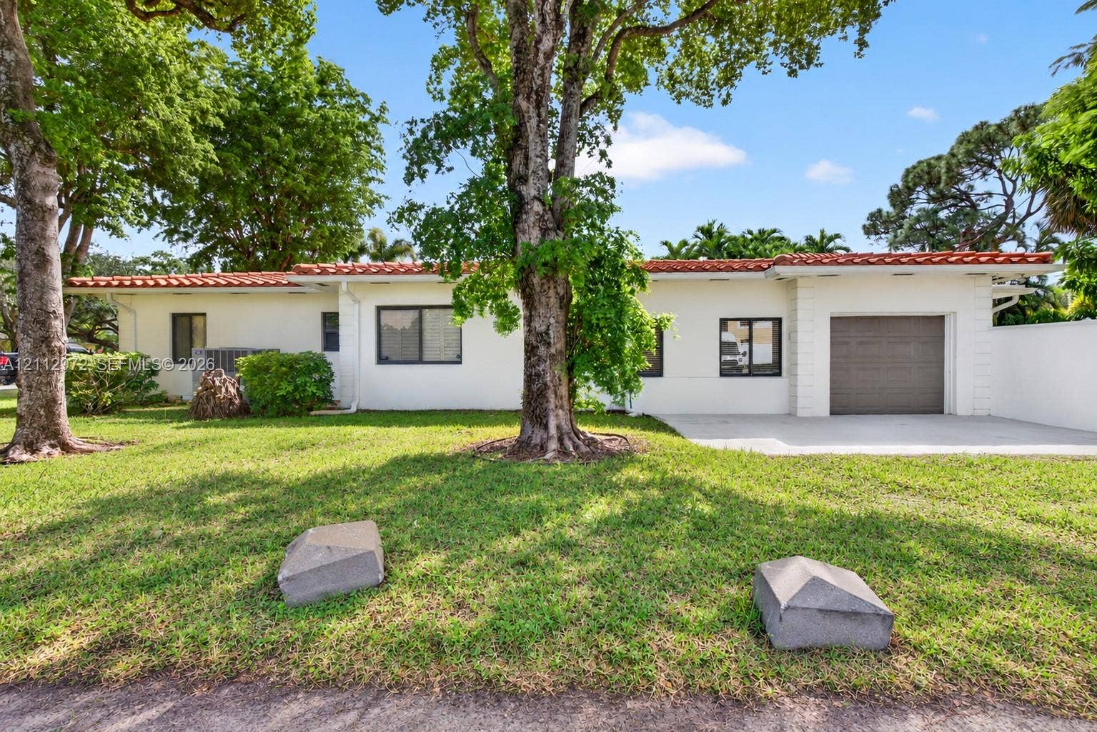 549 NE 12th Avenue, #0, Fort Lauderdale, Fort Lauderdale, FL 33301 Stucco exterior featuring a terracotta tile roof, single-car garage, and mature trees on a landscaped lot