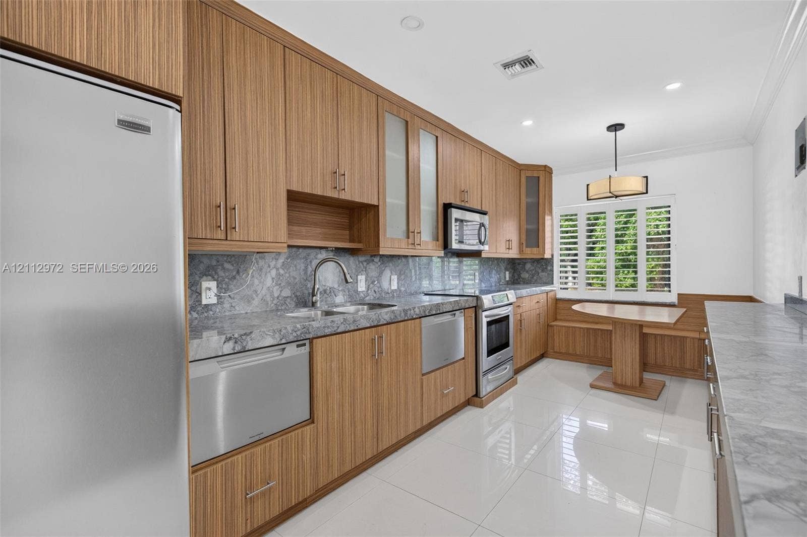 549 NE 12th Avenue, #0, Fort Lauderdale, Fort Lauderdale, FL 33301 Kitchen featuring wood-grain cabinetry, stone countertops with matching backsplash, stainless steel appliances, polished tile flooring, and a built-in bench seating nook