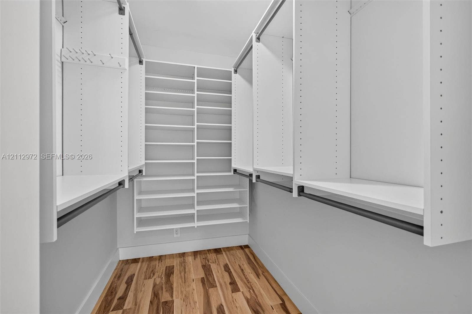 549 NE 12th Avenue, #0, Fort Lauderdale, Fort Lauderdale, FL 33301 Walk-in closet featuring white built-in shelving, multiple hanging rods, and wood-finish flooring