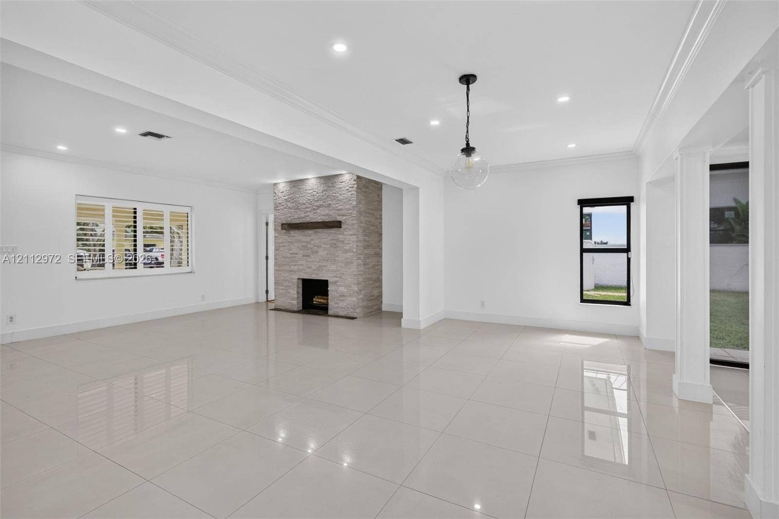 549 NE 12th Avenue, #0, Fort Lauderdale, Fort Lauderdale, FL 33301 Open-concept interior featuring light-toned tile flooring, a floor-to-ceiling stacked stone fireplace with a wood mantel, recessed lighting, and a modern glass pendant fixture