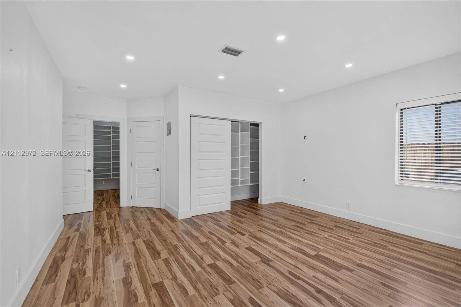 549 NE 12th Avenue, #0, Fort Lauderdale, Fort Lauderdale, FL 33301 Room featuring wood-finish flooring, recessed lighting, white horizontal-panel doors, and built-in shelving within the closet space