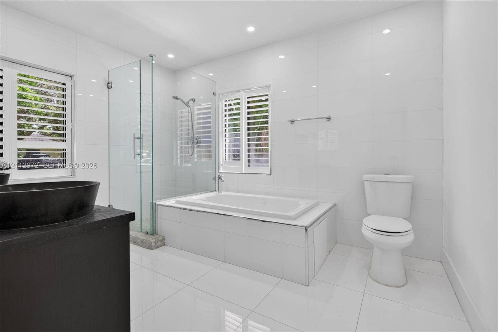 549 NE 12th Avenue, #0, Fort Lauderdale, Fort Lauderdale, FL 33301 Modern bathroom featuring a glass-enclosed walk-in shower, a deep-soaking bathtub with tile surround, plantation shutters, and a dark-finish vanity with a vessel sink