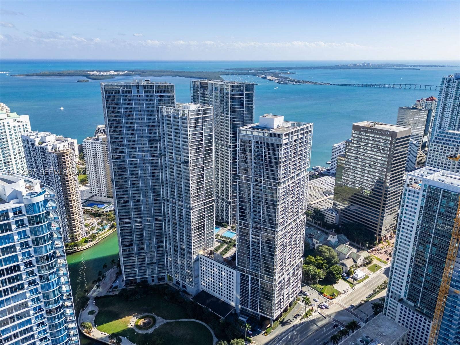 High-rise residential towers featuring glass-curtain facades, set along a coastal waterfront with proximity to a public park