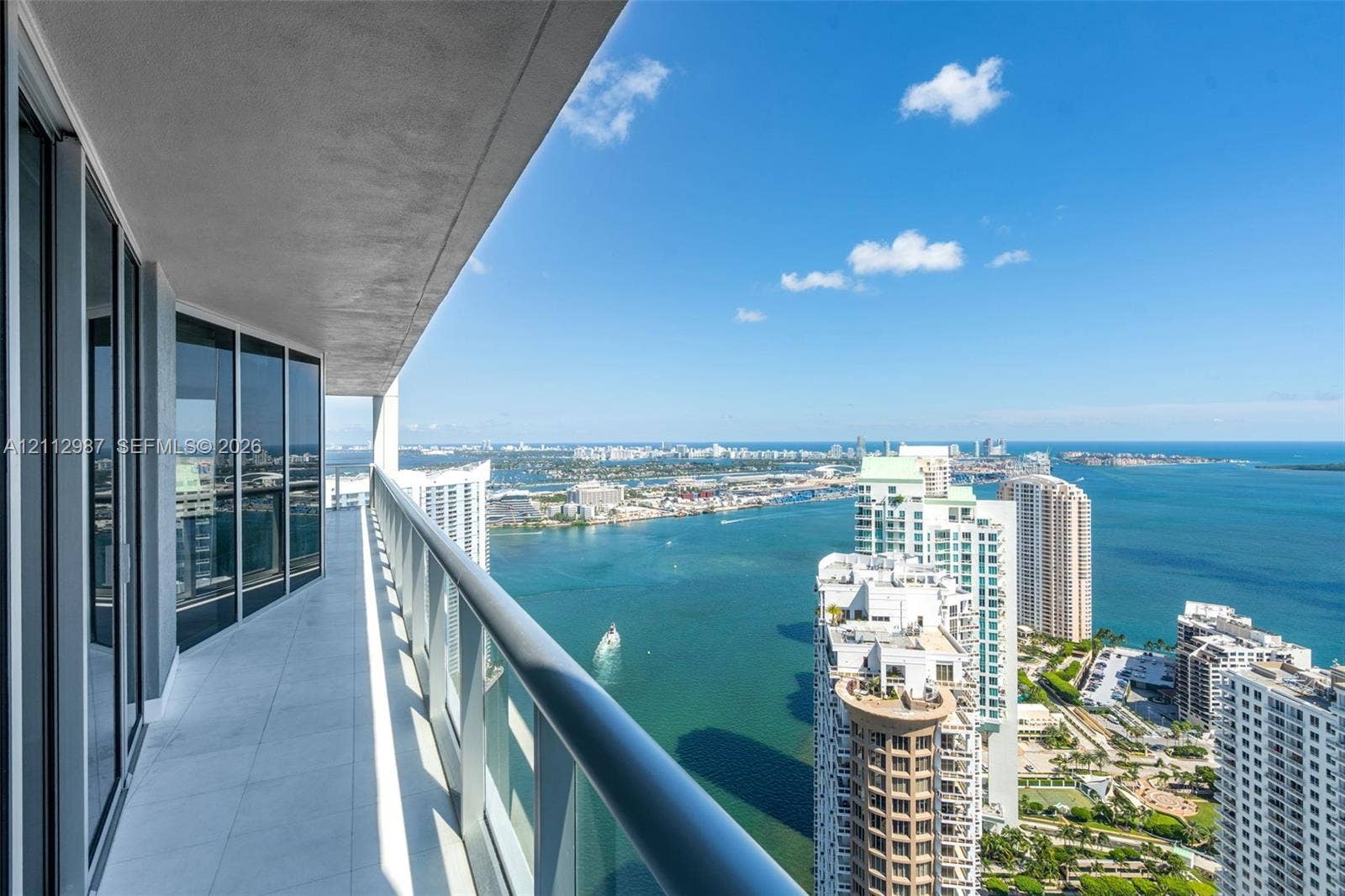 Covered balcony featuring tile flooring and a glass panel railing