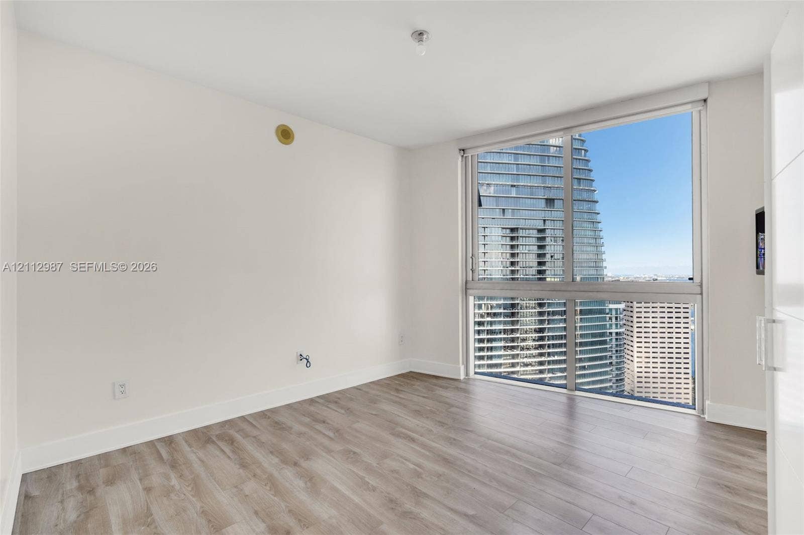 Floor-to-ceiling windows, wood-finish flooring, and white walls