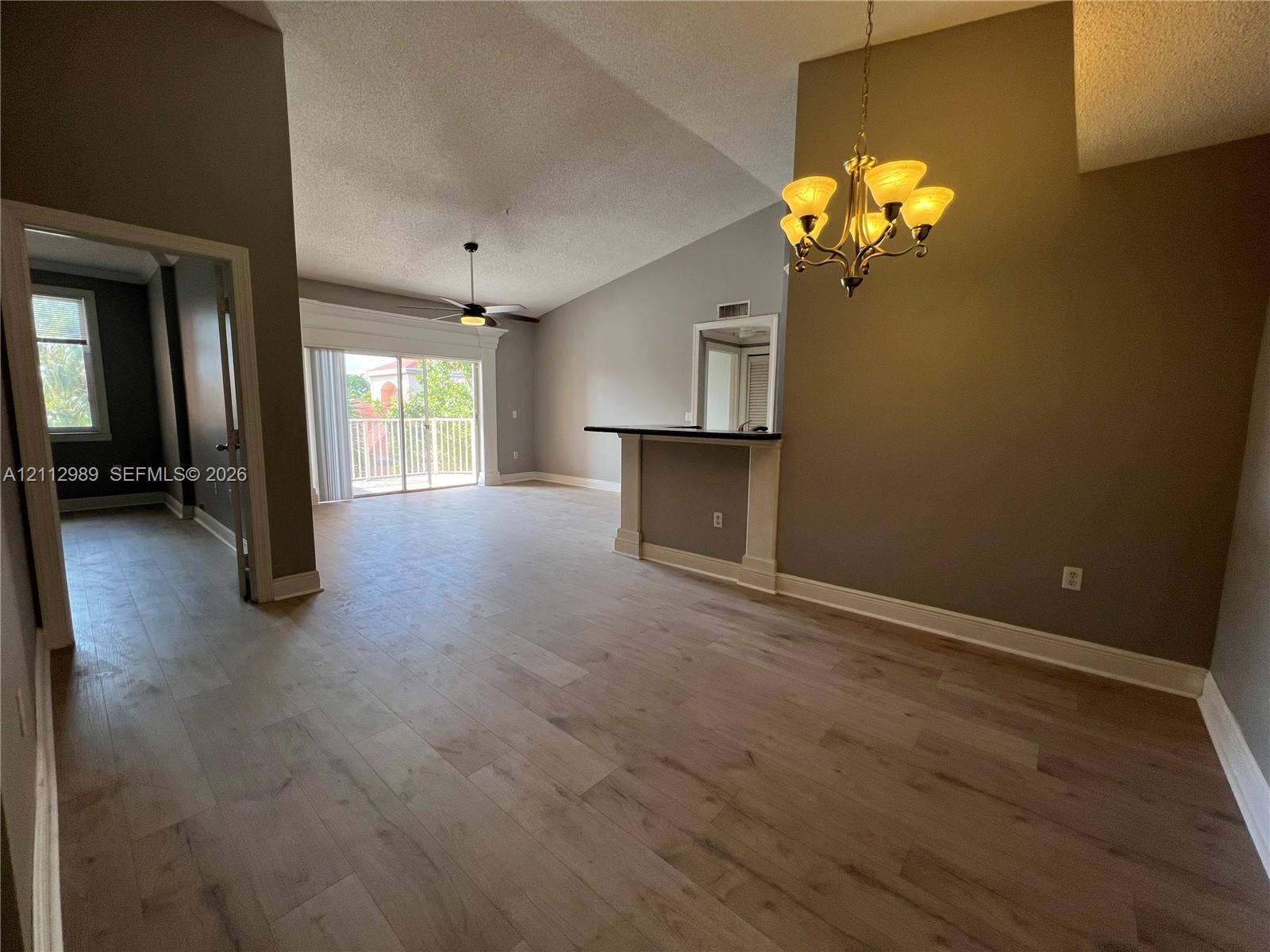 Vaulted ceilings, wood-finish flooring, built-in bar, and multi-light chandelier