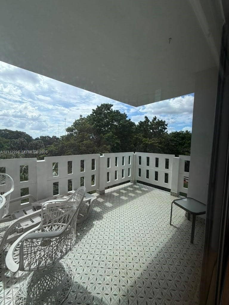 Covered balcony featuring geometric patterned tile flooring and a decorative concrete balustrade