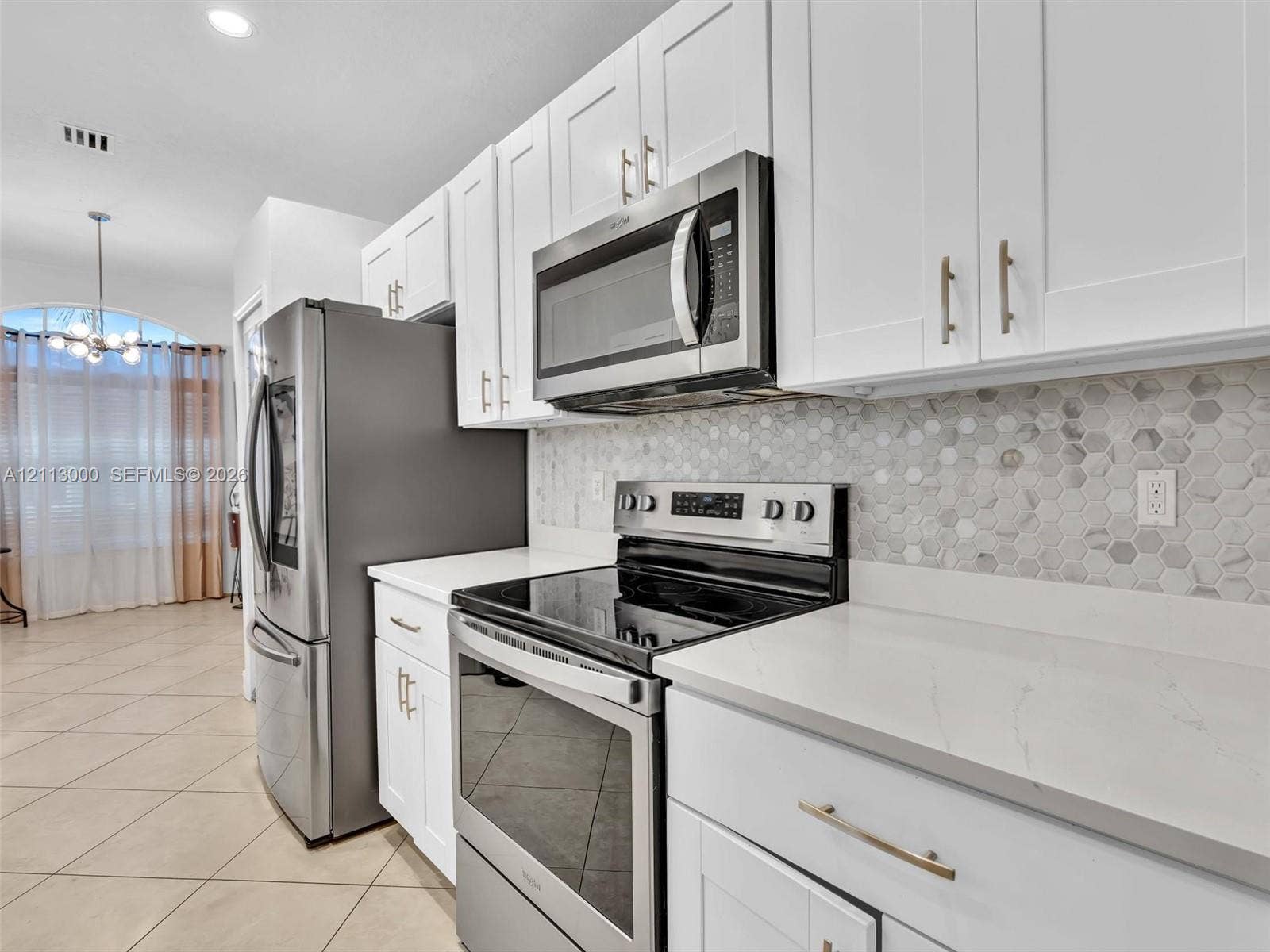 10860 La Salinas Circle, Boca Raton, FL 33428 Kitchen featuring white shaker-style cabinetry, stainless steel appliances, quartz countertops, and a hexagonal tile backsplash