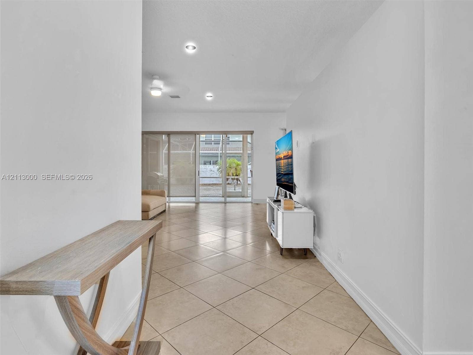 10860 La Salinas Circle, Boca Raton, FL 33428 Neutral ceramic tile flooring, recessed ceiling lighting, and sliding glass doors leading to a screened-in enclosure