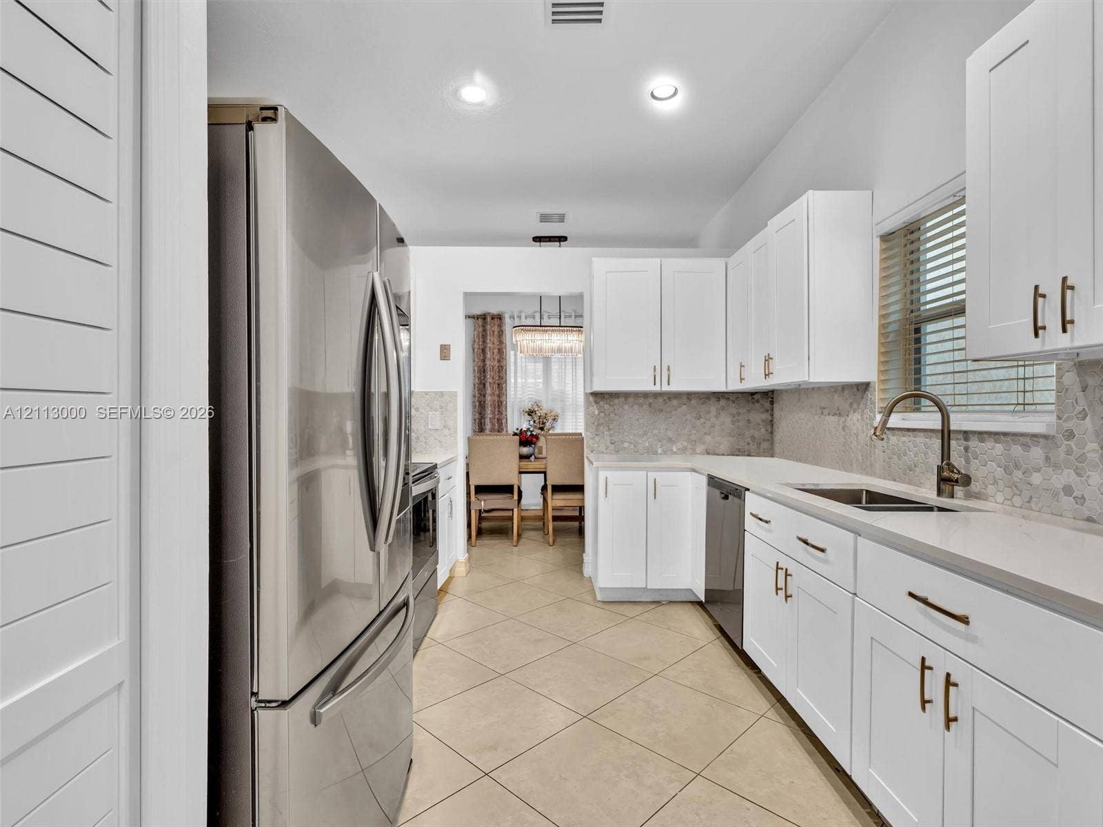 10860 La Salinas Circle, Boca Raton, FL 33428 Kitchen featuring white shaker-style cabinetry, stainless steel refrigerator, stone-composite countertops, mosaic tile backsplash, and tile flooring