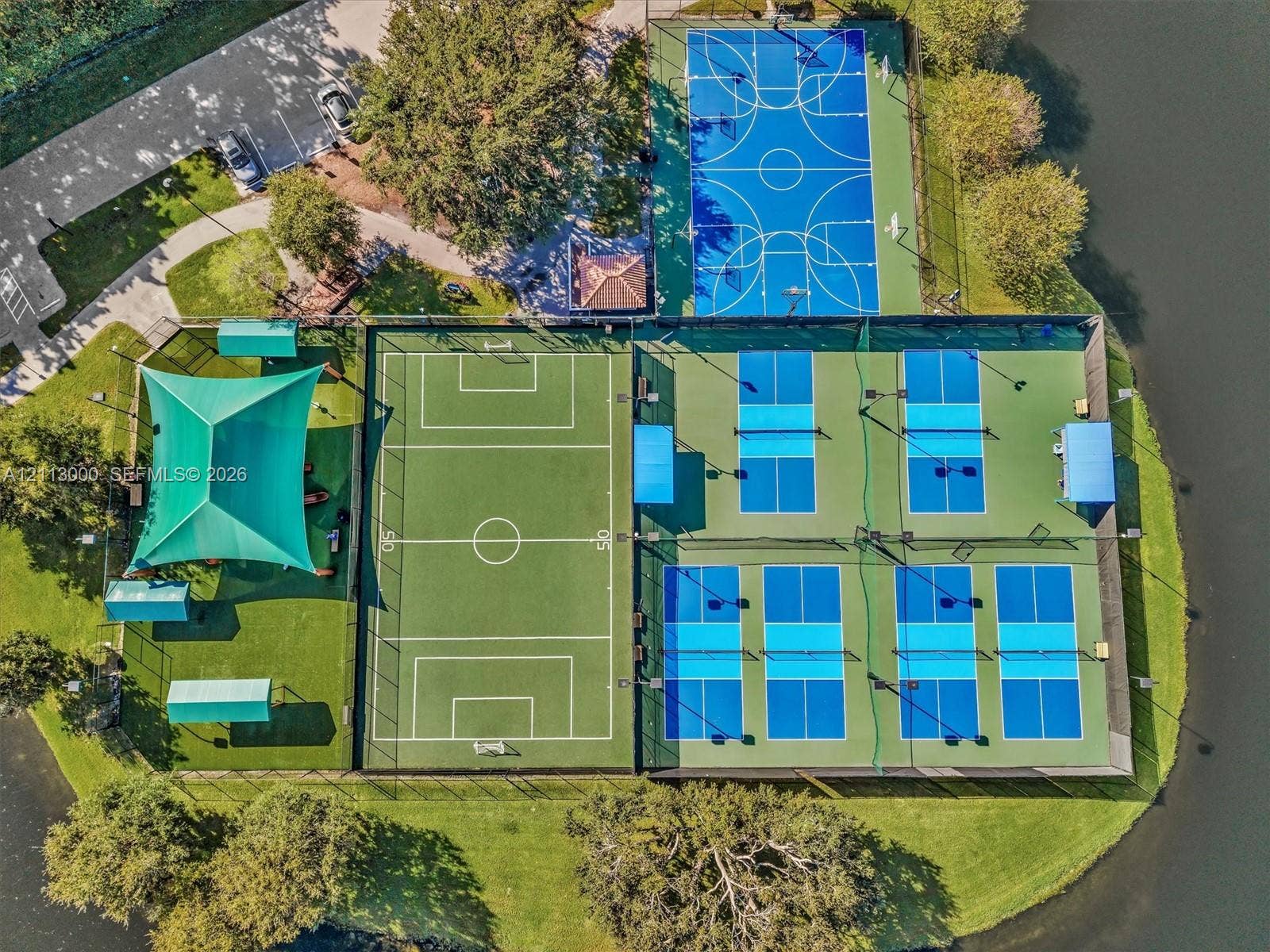 10860 La Salinas Circle, Boca Raton, FL 33428 Recreational complex featuring a full-size basketball court, multi-purpose athletic field with sun shade canopy, and multiple pickleball courts situated along the waterfront