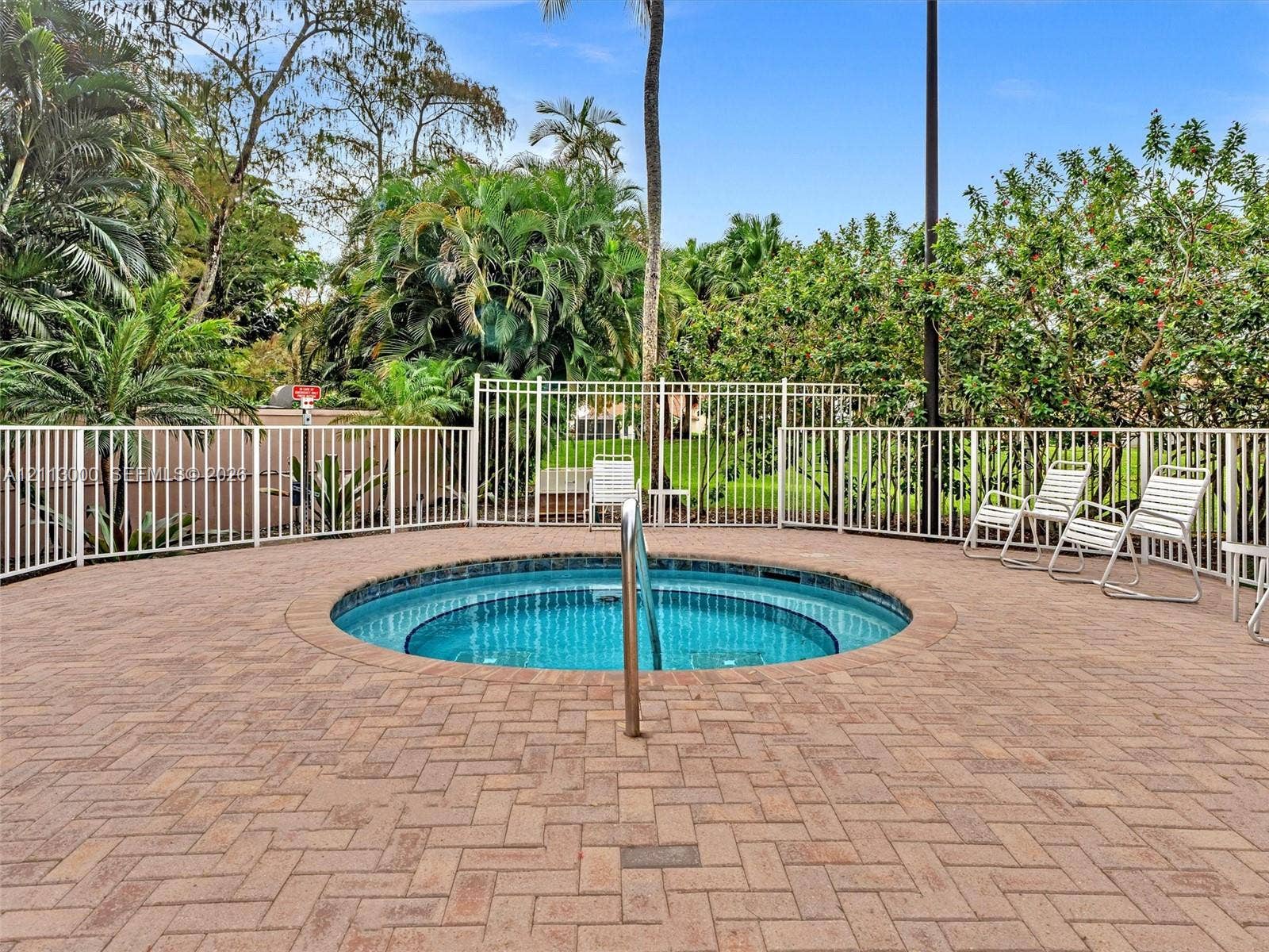 10860 La Salinas Circle, Boca Raton, FL 33428 In-ground circular spa featuring a tile finish, metal handrail, brick paver decking in a herringbone pattern, and perimeter metal fencing