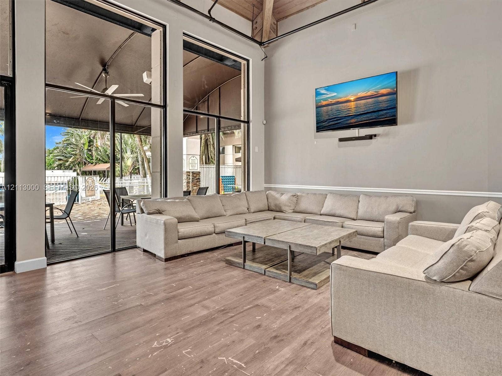 10860 La Salinas Circle, Boca Raton, FL 33428 High-ceilinged common area featuring wood-finish flooring, exposed structural beams, floor-to-ceiling windows, and wall-mounted chair rail molding