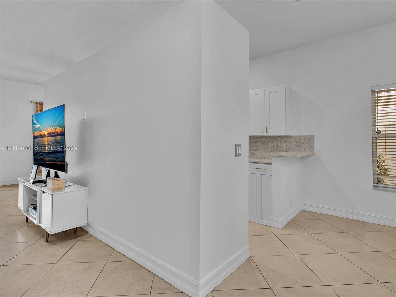 10860 La Salinas Circle, Boca Raton, FL 33428 Tile flooring, white Shaker-style cabinetry, neutral stone-finish countertops, and a decorative tile backsplash