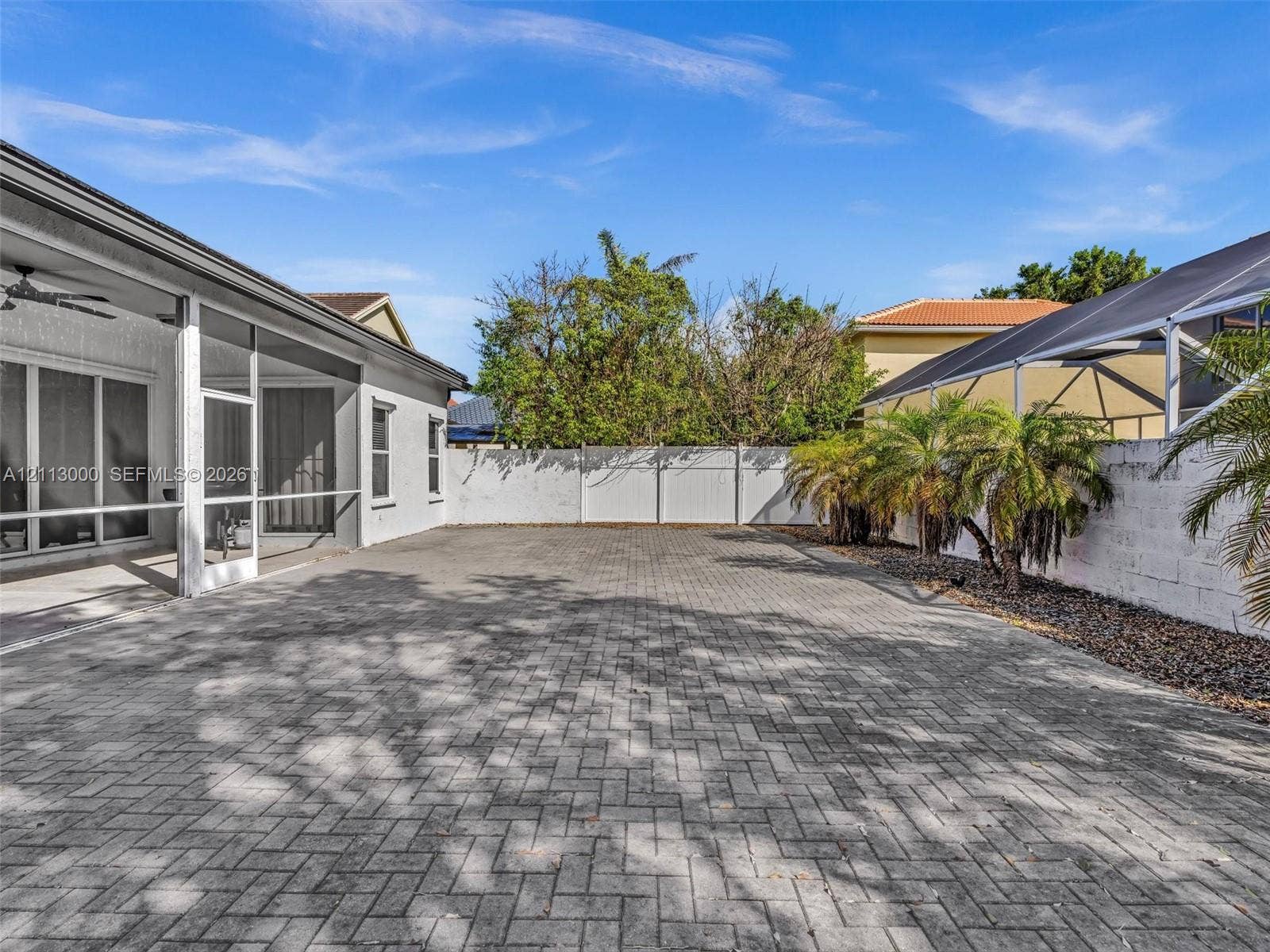 10860 La Salinas Circle, Boca Raton, FL 33428 Screened-in covered lanai featuring paved patio flooring and a white privacy fence