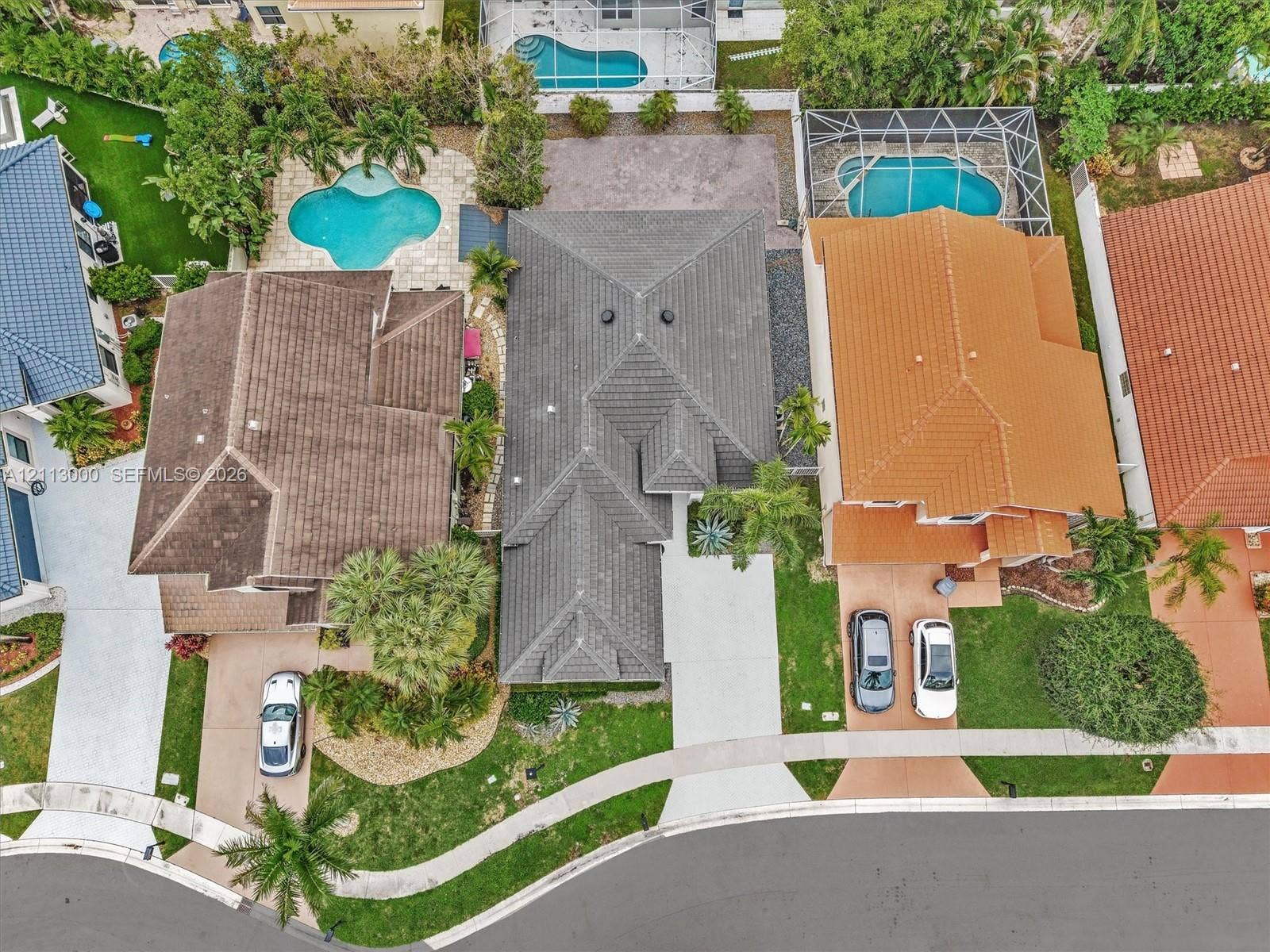 10860 La Salinas Circle, Boca Raton, FL 33428 Aerial perspective featuring a multi-pitched tile roof, concrete driveway, stone-paved walkway, and landscaped front yard