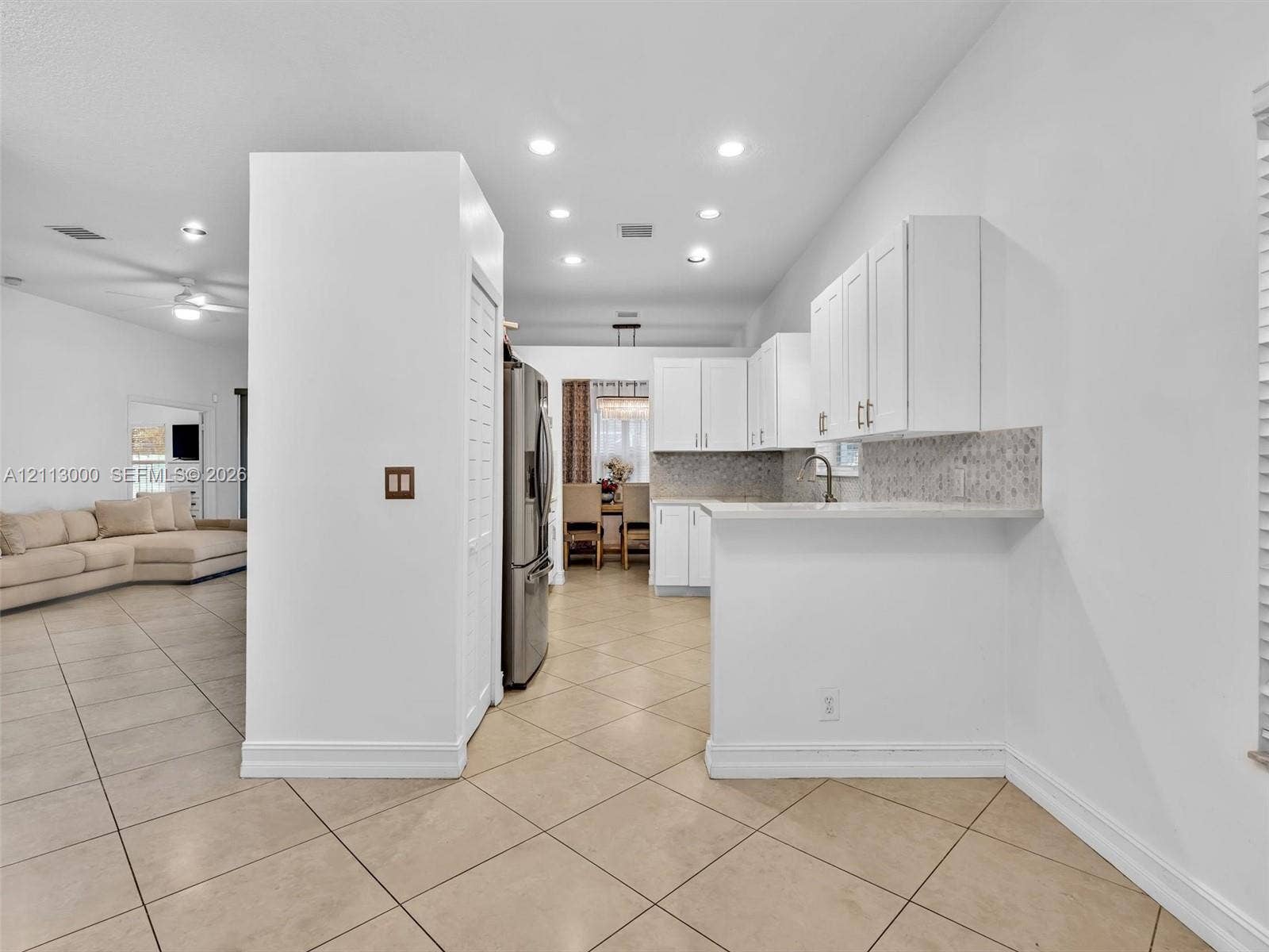 10860 La Salinas Circle, Boca Raton, FL 33428 Kitchen featuring white cabinetry, solid-surface countertops, tile backsplash, stainless steel refrigerator, and recessed lighting