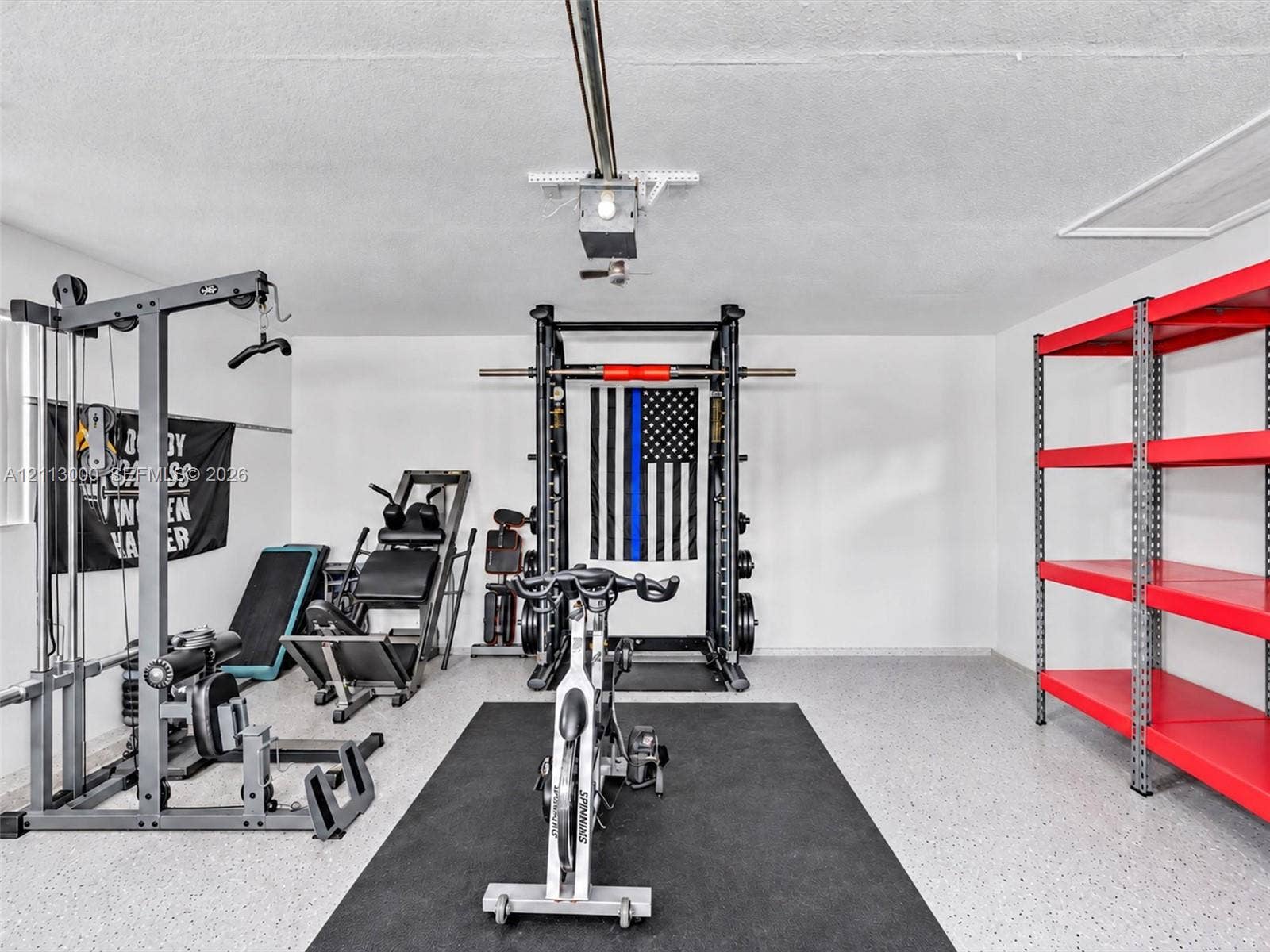 10860 La Salinas Circle, Boca Raton, FL 33428 Garage space featuring an epoxy-coated floor, an automated overhead door opener, and a ceiling-mounted access hatch