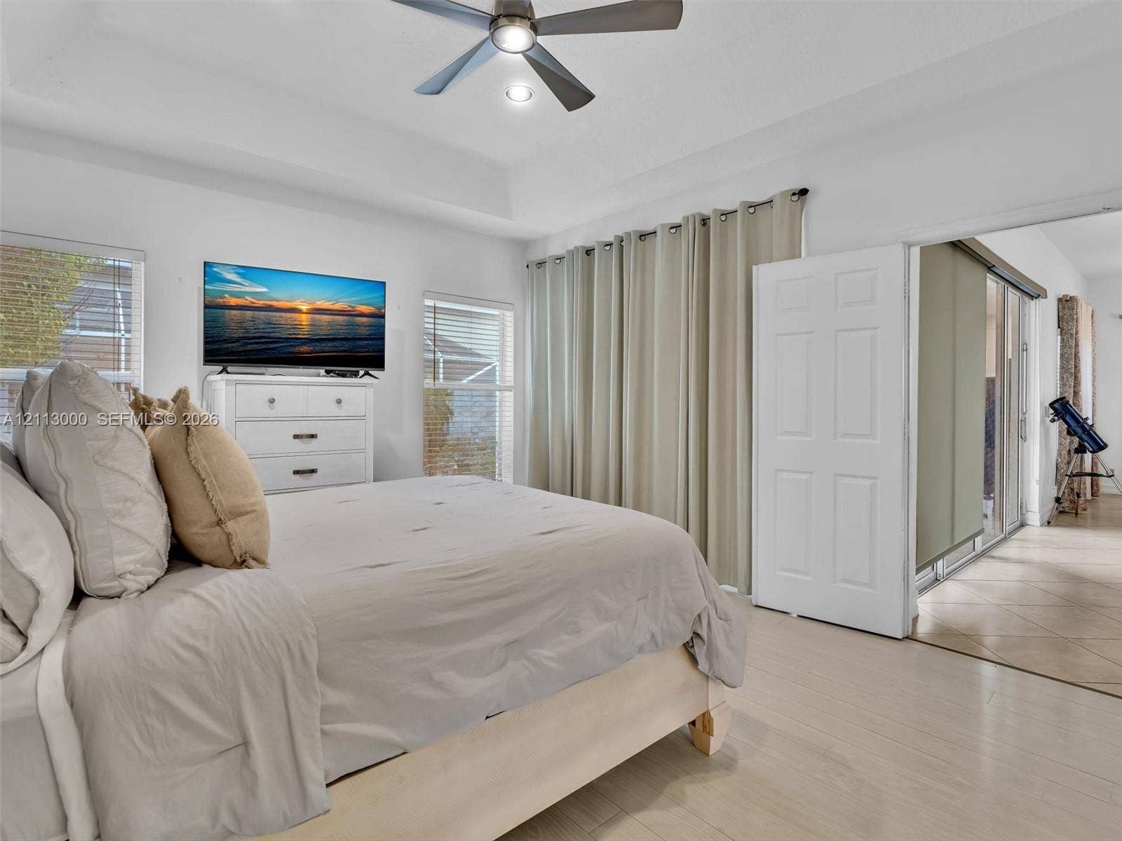 10860 La Salinas Circle, Boca Raton, FL 33428 Tray ceiling with a central multi-blade ceiling fan, neutral wall finishes, tile flooring, and dual-panel interior doors