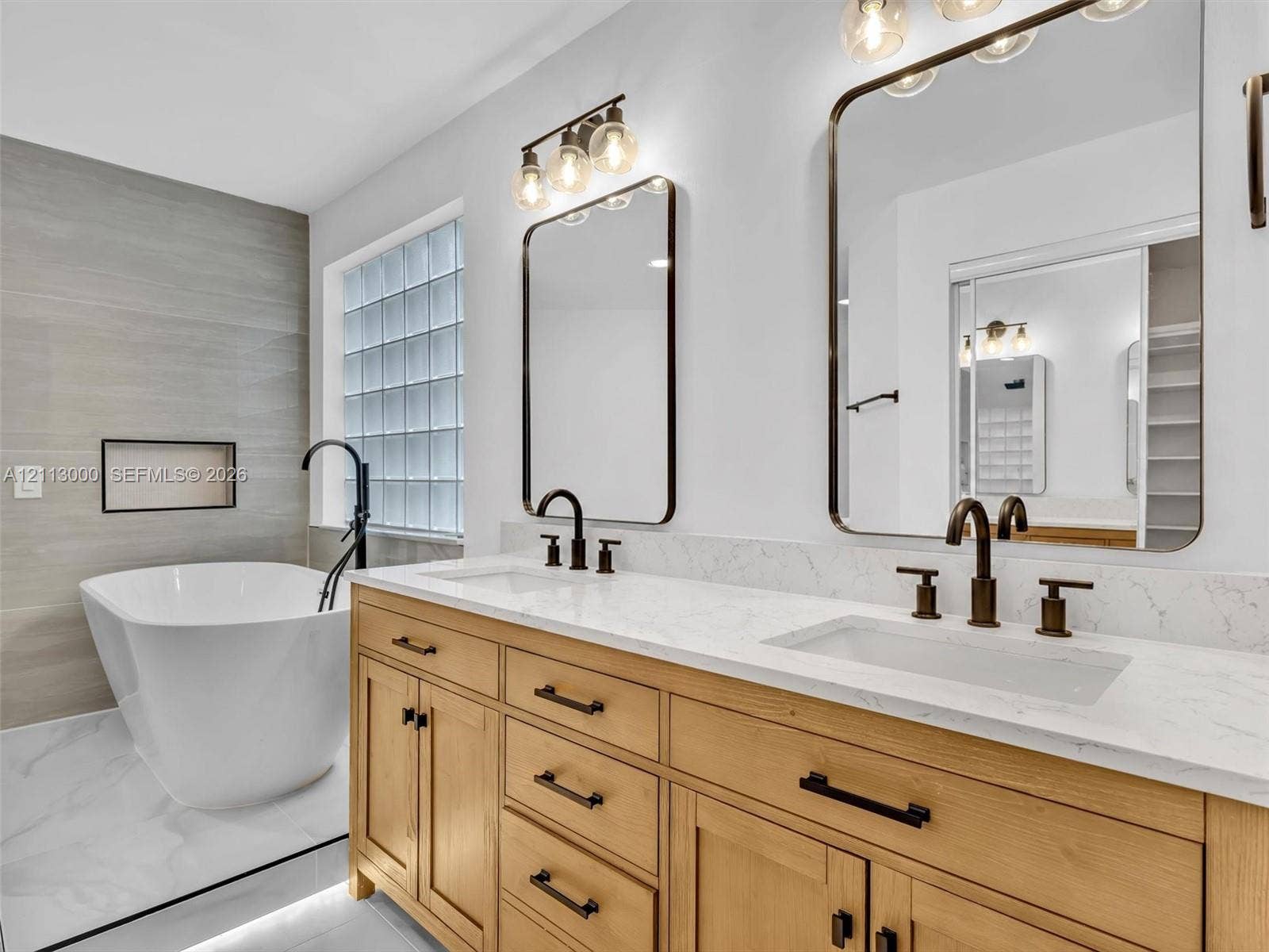 10860 La Salinas Circle, Boca Raton, FL 33428 Double vanity featuring natural wood cabinetry, white stone-composite countertops, rectangular undermount sinks, and matte black fixtures