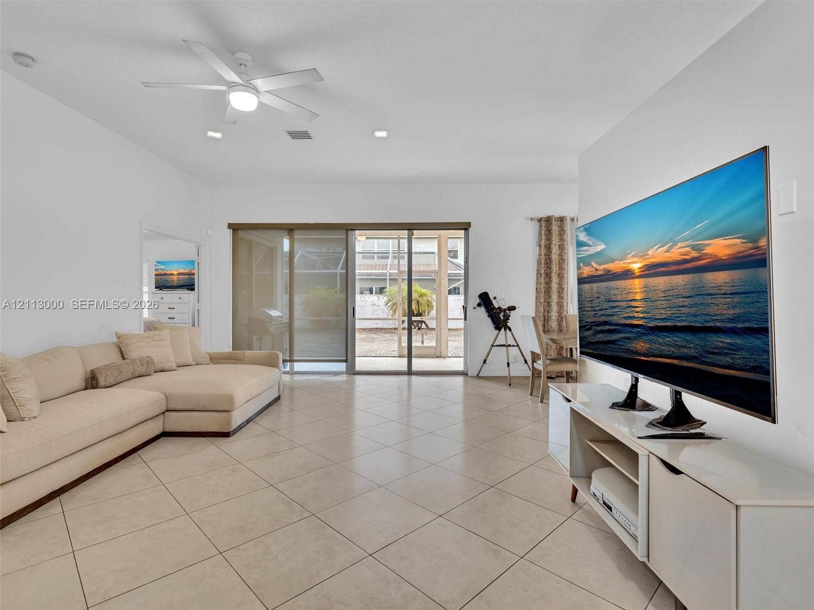 10860 La Salinas Circle, Boca Raton, FL 33428 Open-concept interior featuring large-format diagonal tile flooring, high ceilings with a centralized lighted ceiling fan, and sliding glass doors with screen enclosure