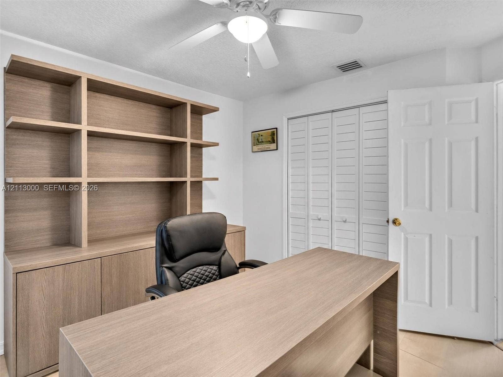 10860 La Salinas Circle, Boca Raton, FL 33428 Built-in wood-finish shelving unit, white louvered-style bi-fold closet doors, and ceiling-mounted light fixture