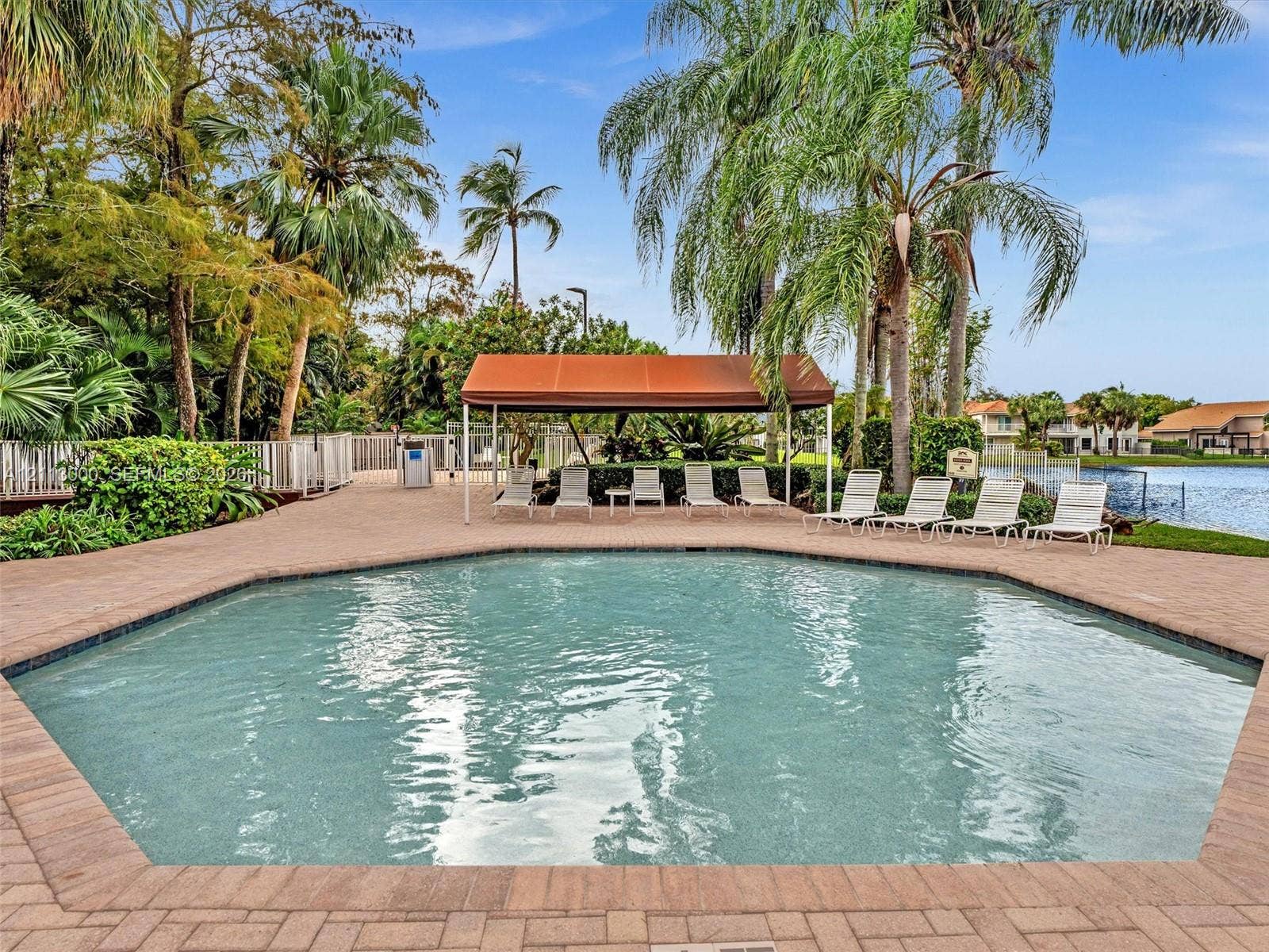 10860 La Salinas Circle, Boca Raton, FL 33428 Swimming pool featuring a paver deck, permanent poolside canopy, and water backdrop