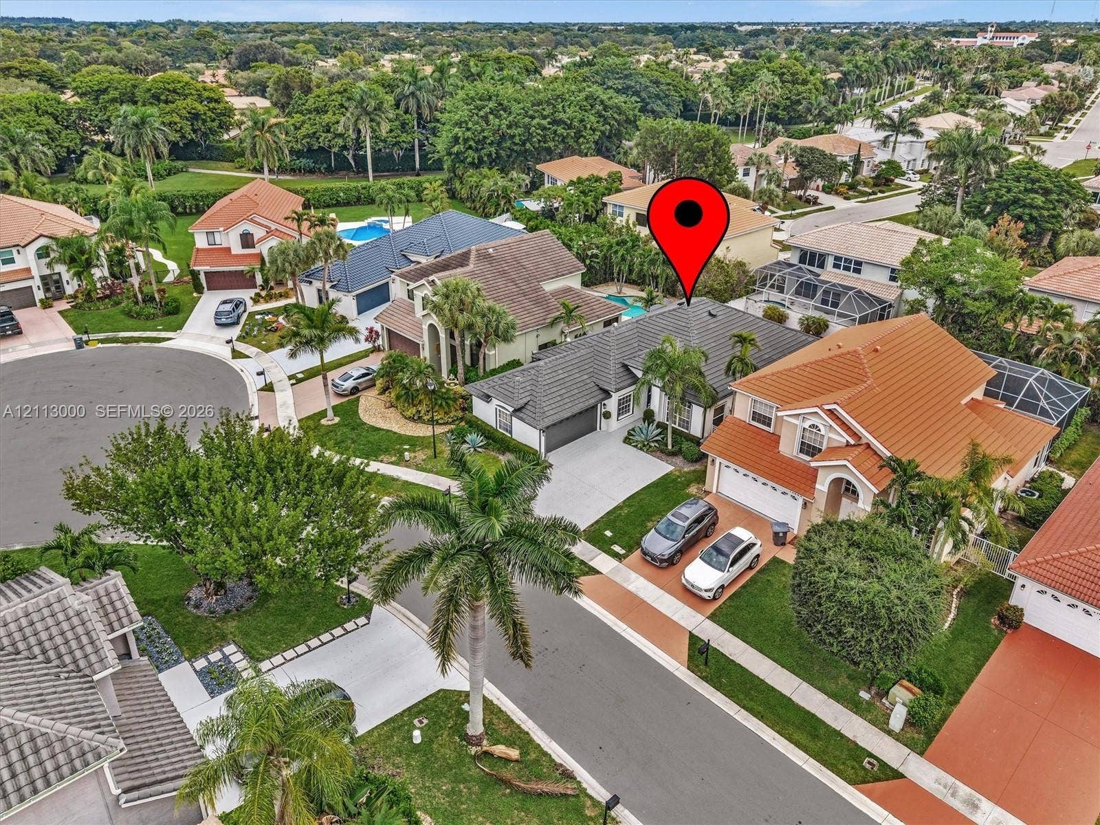 10860 La Salinas Circle, Boca Raton, FL 33428 Aerial perspective of a residential property featuring a concrete tile roof, attached multi-car garage, concrete driveway, and established landscaping