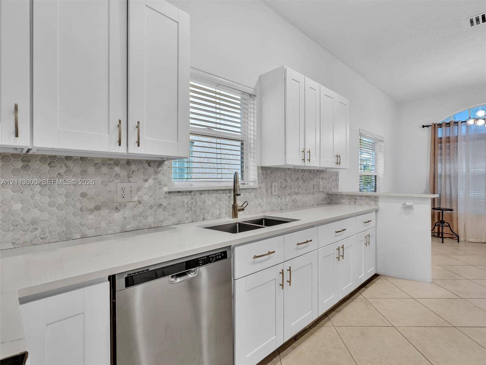 10860 La Salinas Circle, Boca Raton, FL 33428 Kitchen featuring white shaker-style cabinetry, a stone hexagonal tile backsplash, quartz countertops, a stainless steel dishwasher, and a gooseneck faucet
