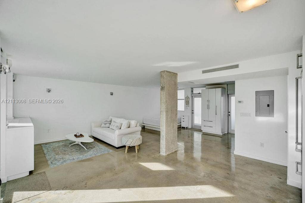 Open-concept interior featuring polished concrete flooring, an exposed structural concrete column, recessed lighting, and built-in white cabinetry