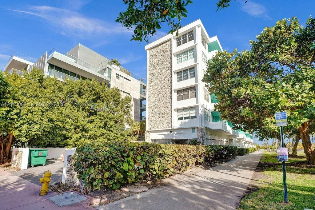 Mid-century modern architectural exterior featuring natural stone facade accents, white smooth-stucco finish, multi-story private balconies, and horizontal window rows