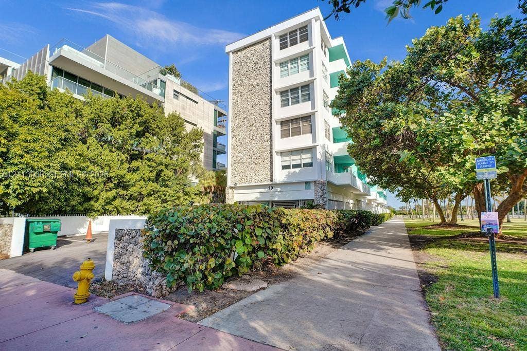 Mid-century modern residential building featuring a stone-clad facade, private balconies, and concrete construction